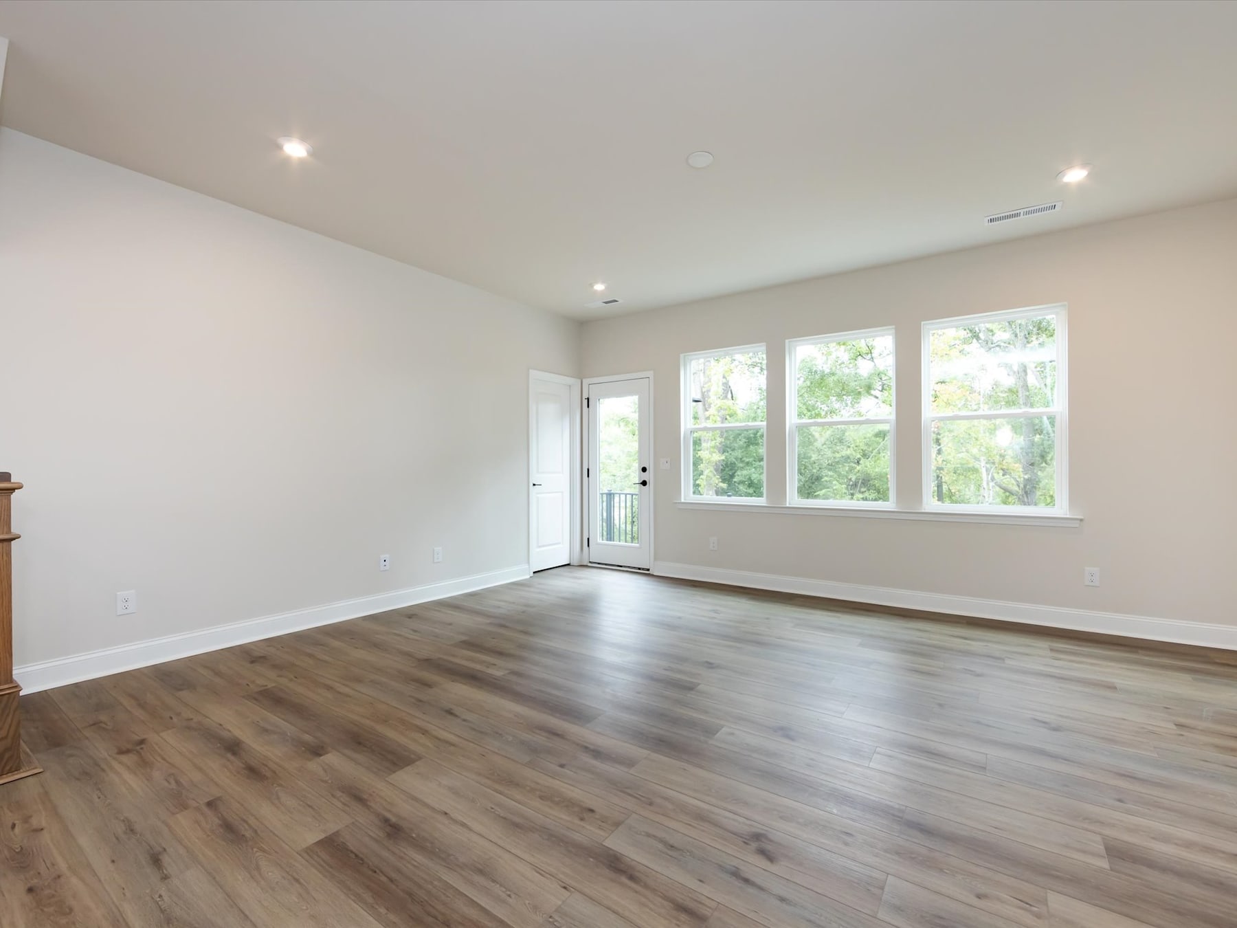 A spacious, well-lit room with hardwood floors, large windows, and a neutral color scheme, creating a bright and airy atmosphere.