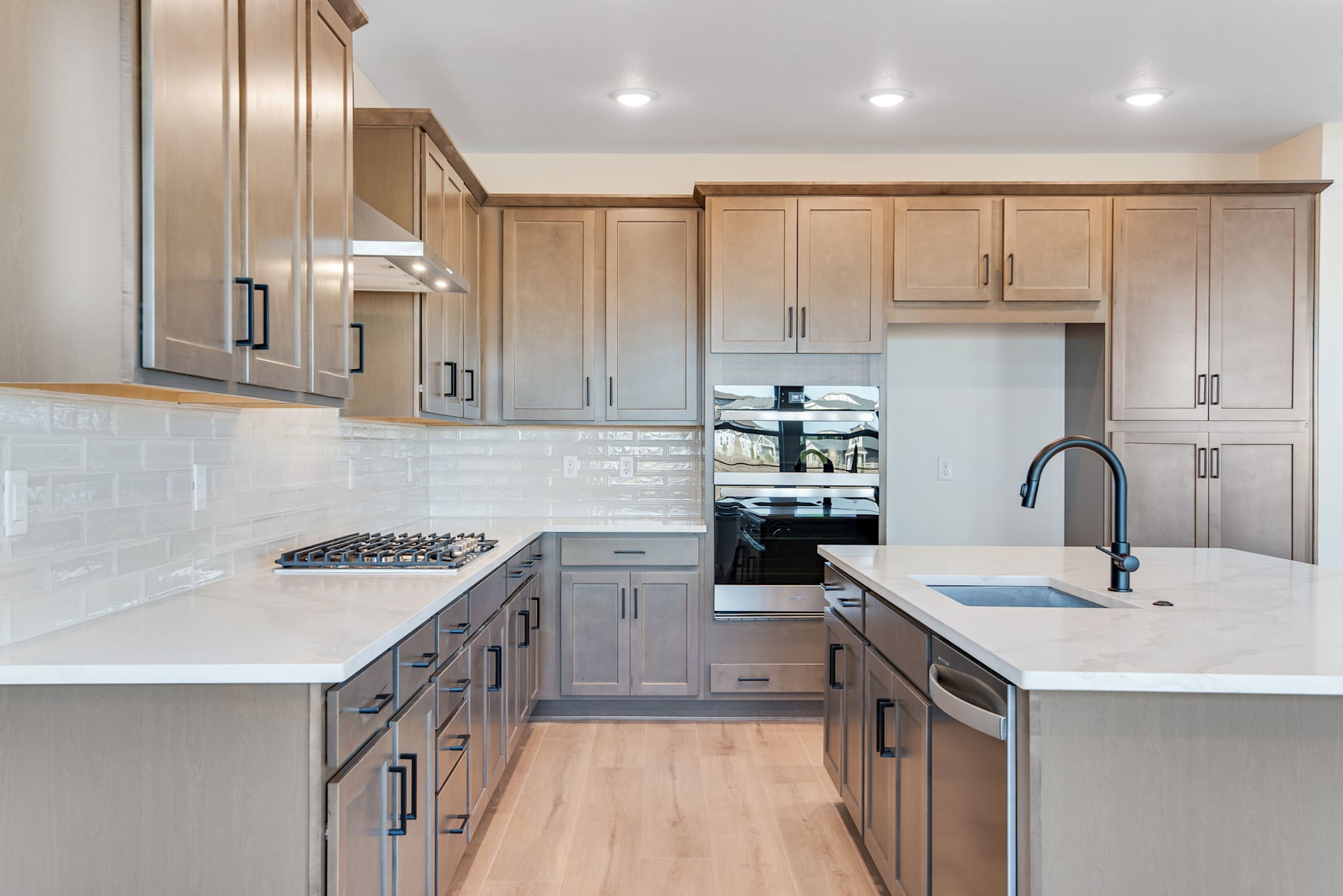 A modern, well-equipped kitchen with light-colored wooden cabinets, white countertops, and stainless steel appliances, creating a clean and inviting atmosphere.