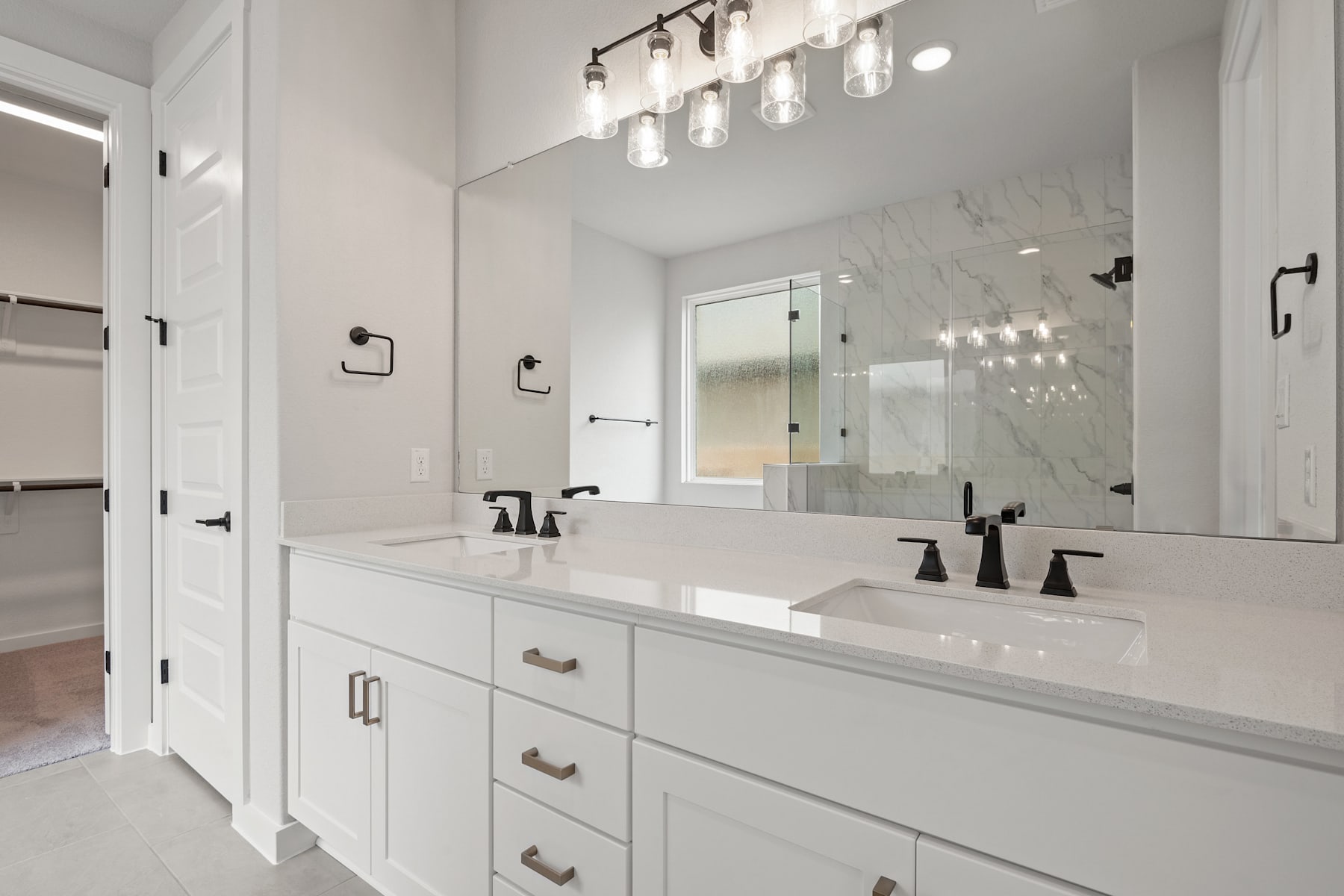 A modern, well-lit bathroom with a double vanity, white cabinets, and a large mirror on the wall, creating a bright and spacious atmosphere.