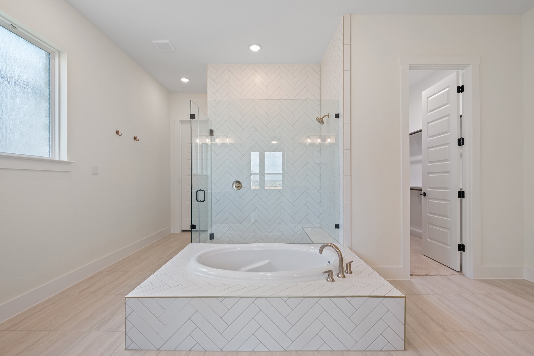 A spacious and modern bathroom with a large white bathtub, a glass shower enclosure, and a wooden floor.