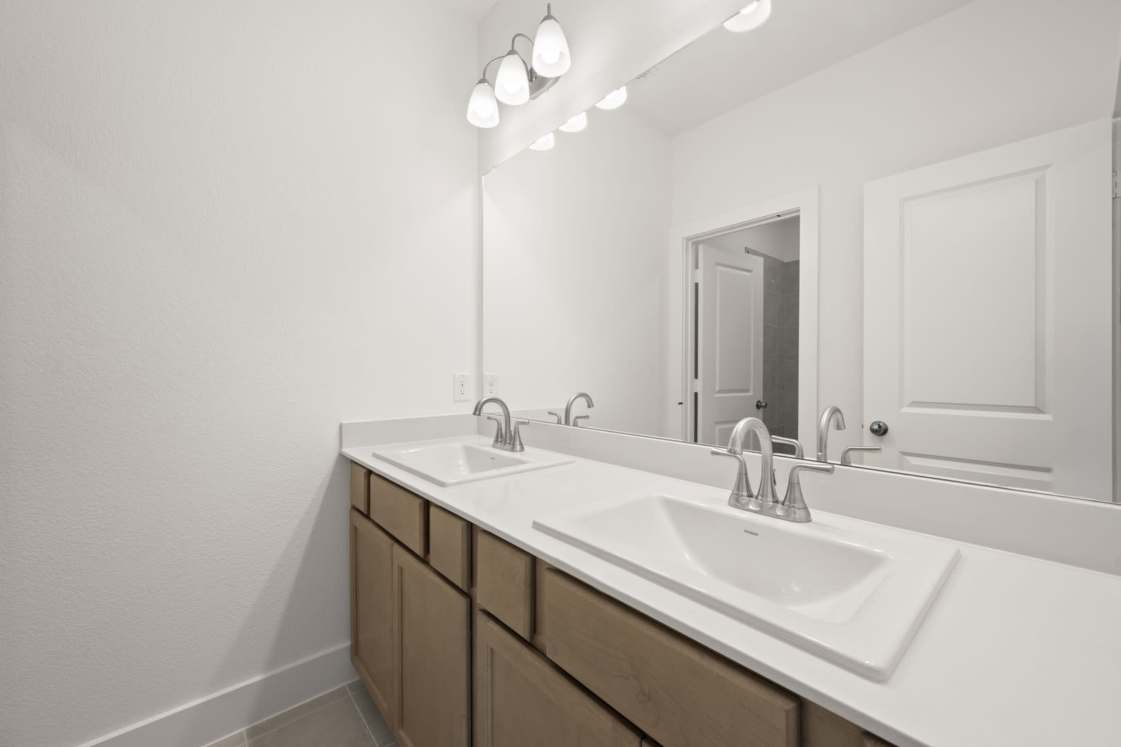 A modern bathroom with a double vanity, white countertop, and recessed lighting fixtures on the ceiling.