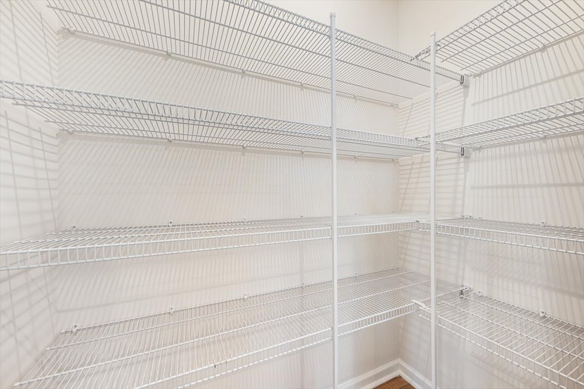 A white, wire-framed shelving unit with multiple levels, occupying the entirety of the frame and creating a sense of depth and organization.