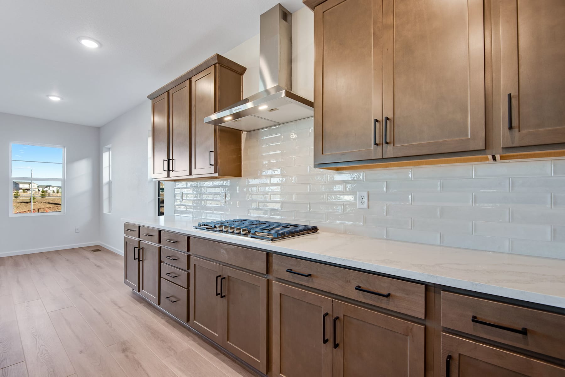 A modern and well-designed kitchen with wooden cabinets, white subway tile backsplash, and a gas stove top.