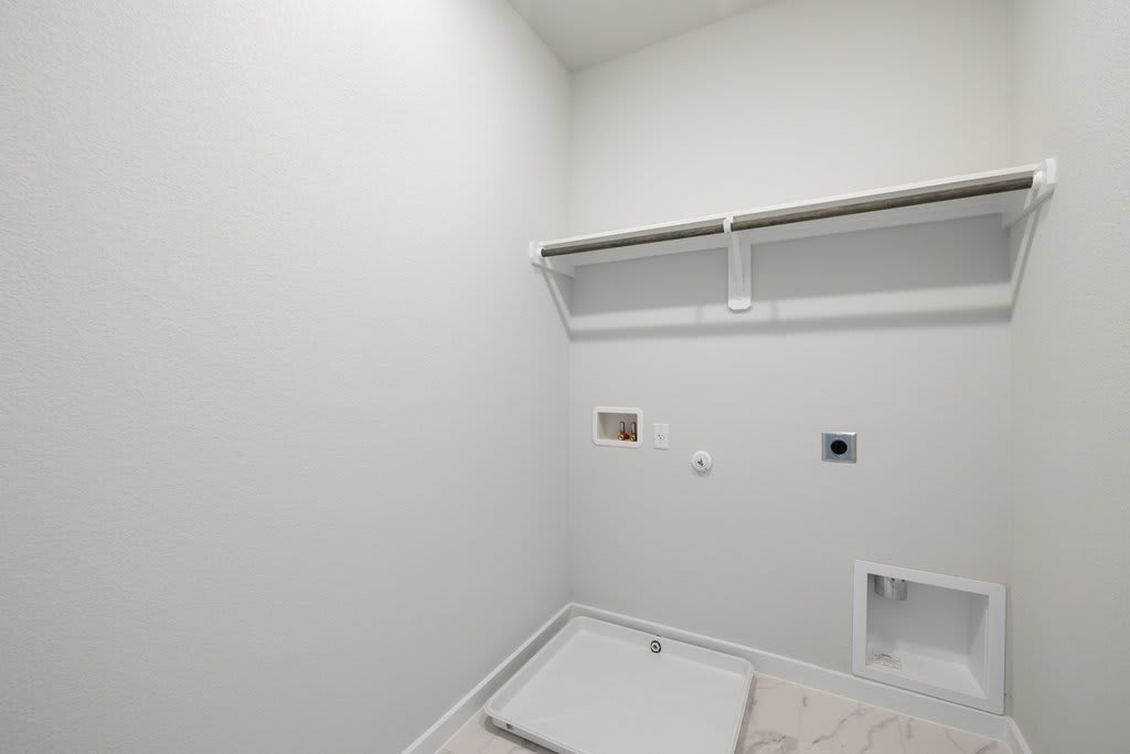 A simple, minimalist closet space with a white wall, a metal clothing rod, and a recessed light fixture.