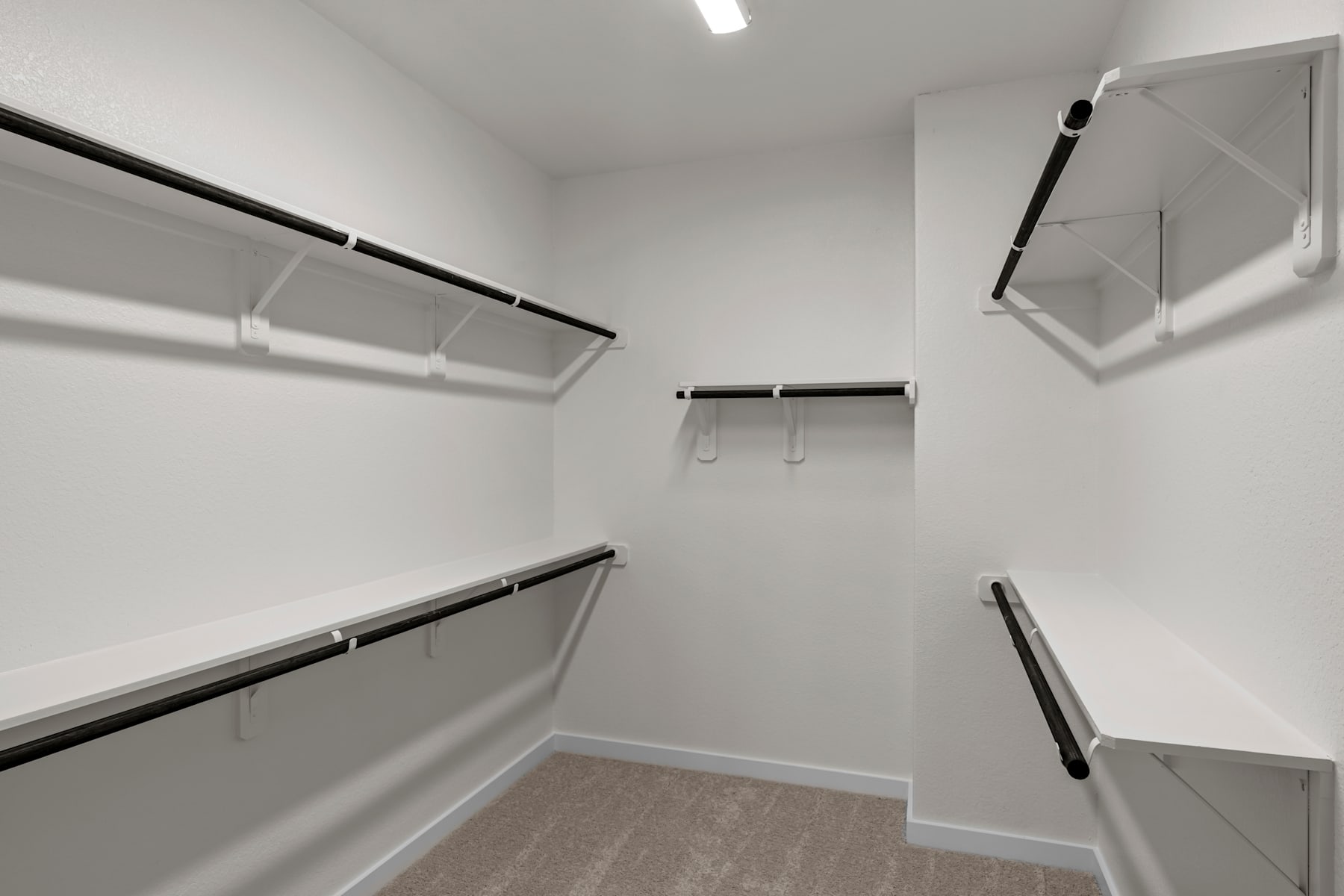 A spacious, well-lit closet with multiple shelves and hanging rods, providing ample storage space.