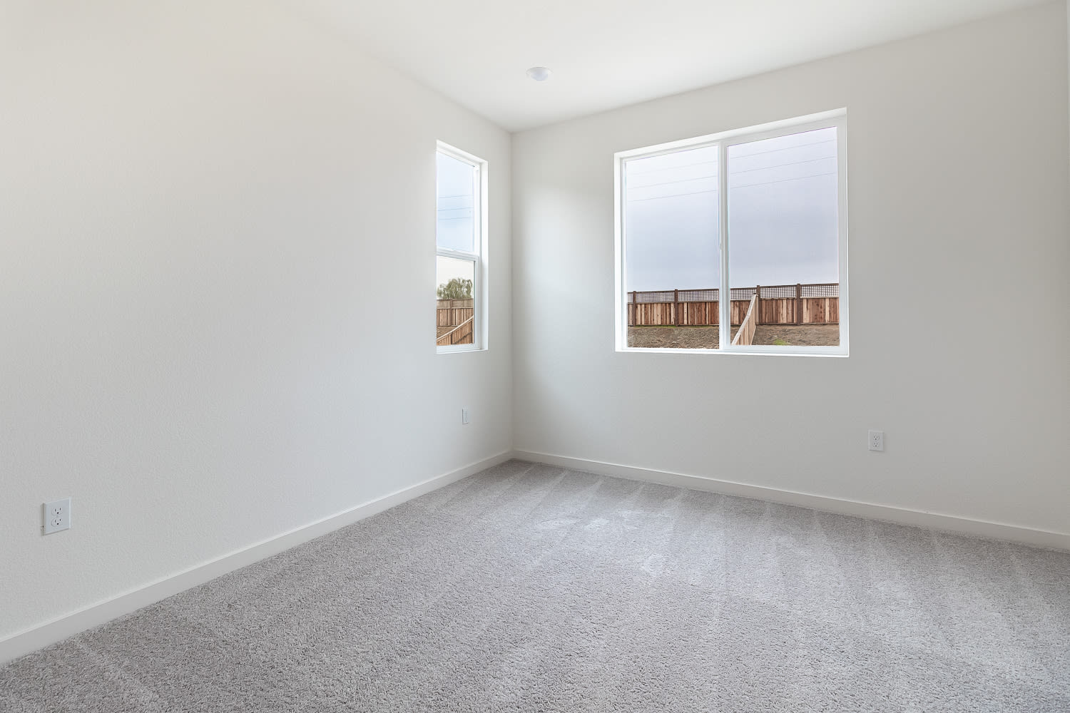 A bright, empty room with white walls, a window, and a carpeted floor.