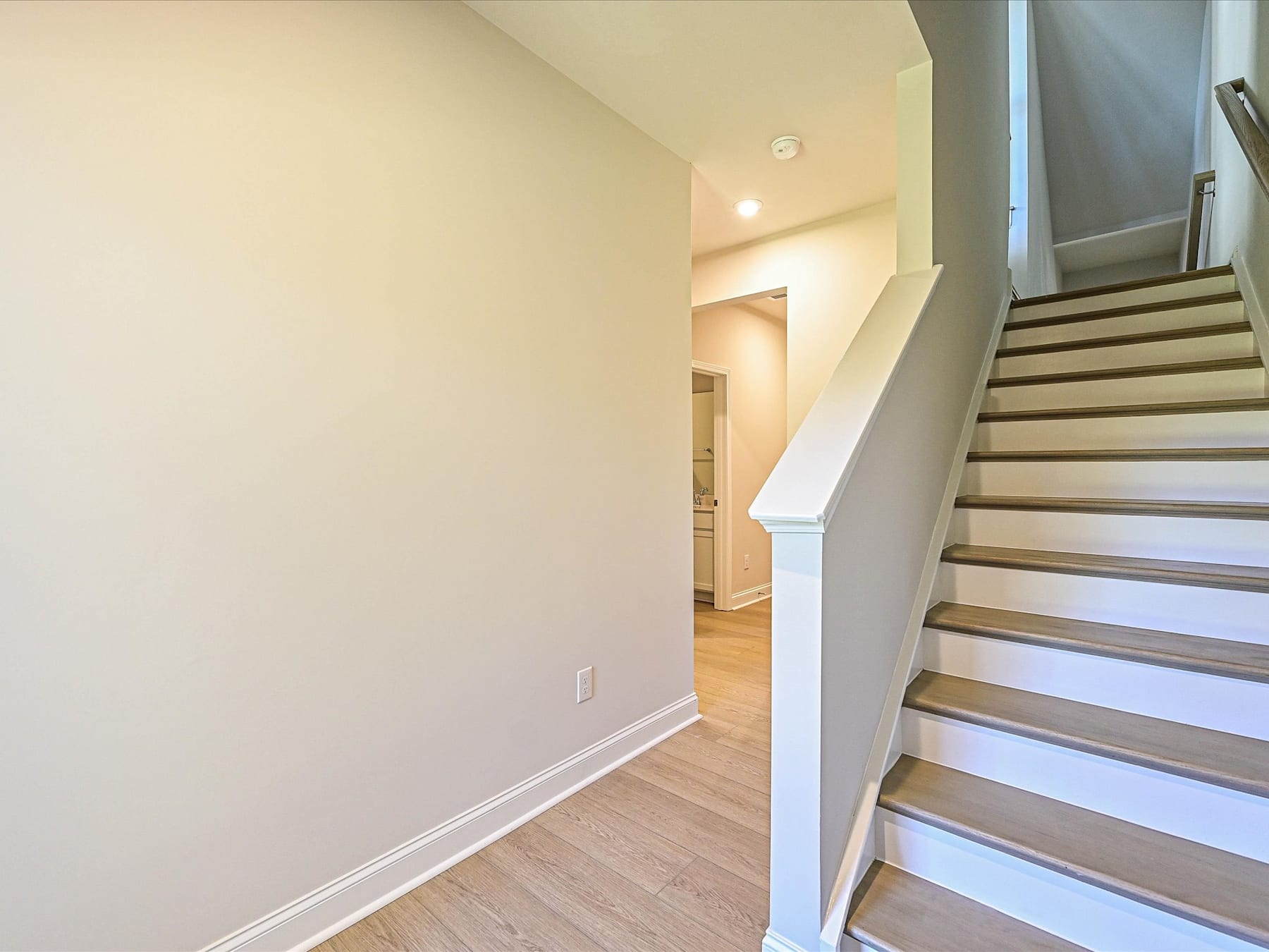 A staircase leading up to a hallway with white walls and wooden floors, creating a bright and inviting atmosphere.