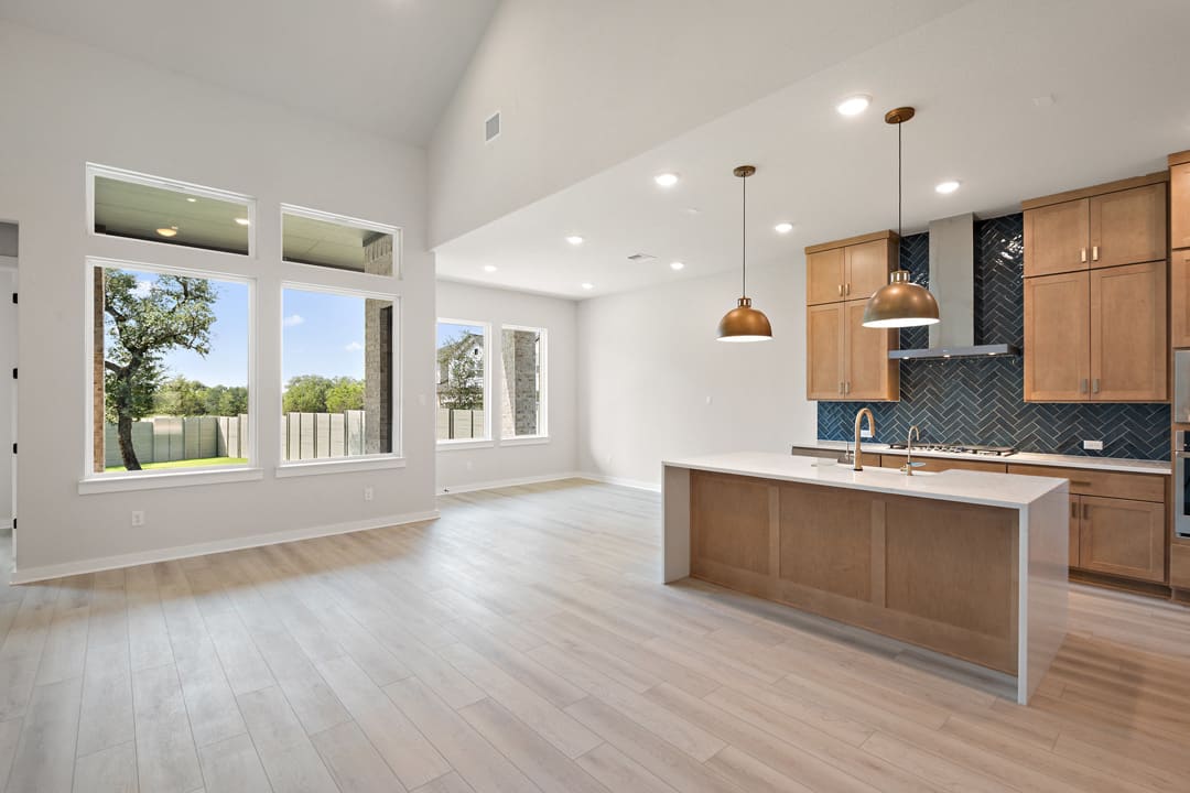 A modern, open-concept kitchen and living space with large windows, hardwood floors, and a mix of natural and industrial design elements.