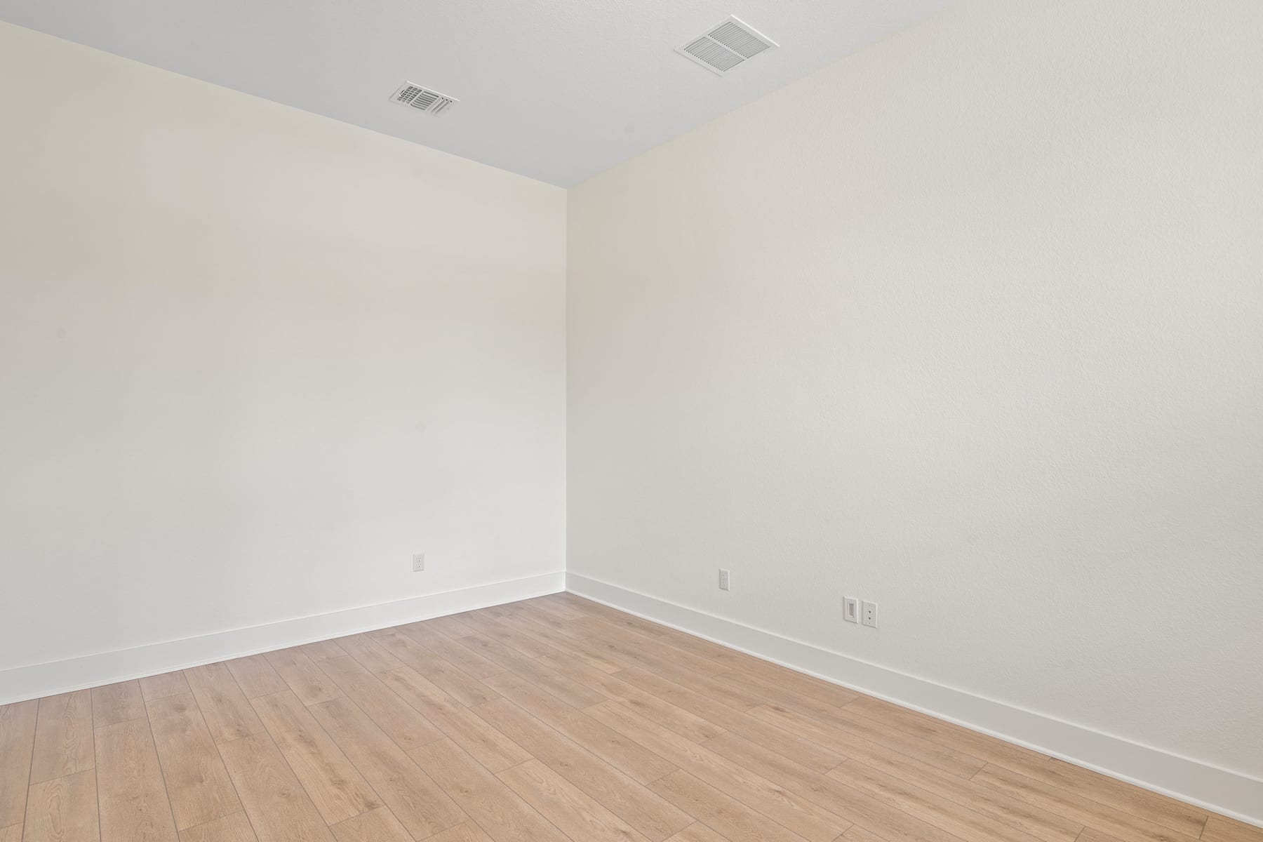 An empty room with white walls and a hardwood floor.