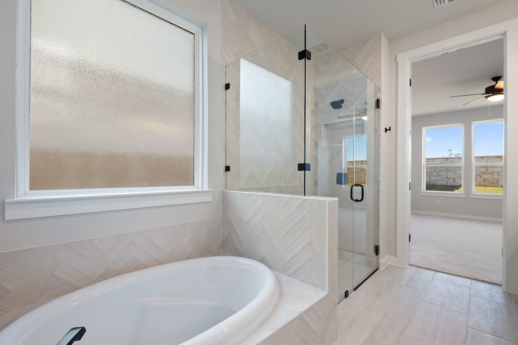 A spacious and modern bathroom with a large window, a freestanding bathtub, and a glass-enclosed shower area.