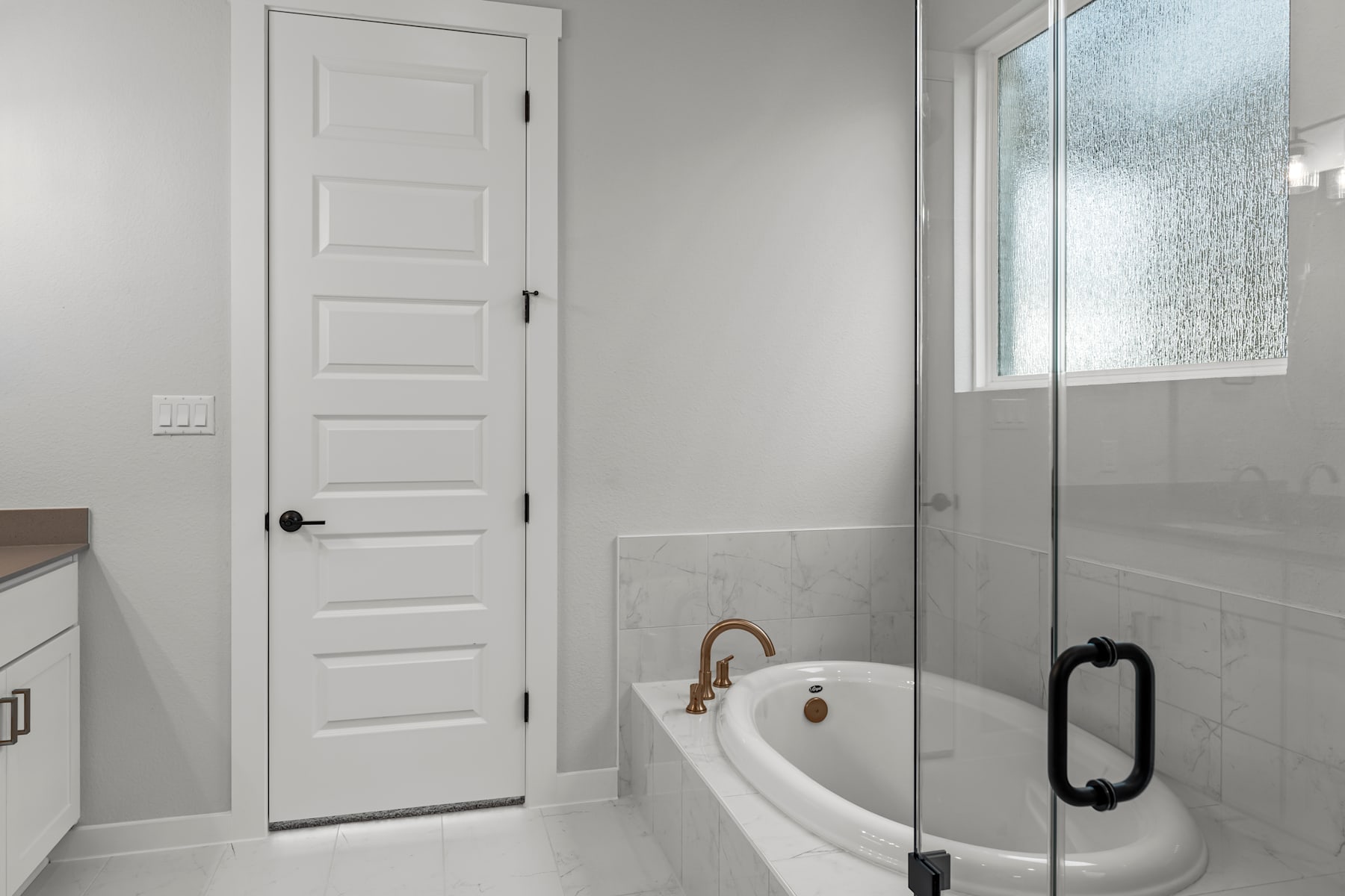 A modern, minimalist bathroom with a white door, a freestanding bathtub, and a glass shower enclosure.