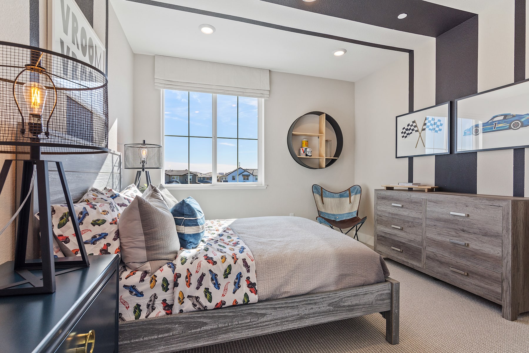 A cozy and stylish bedroom with a wooden bed frame, patterned bedding, and various decorative elements such as a round mirror, wall art, and a floor lamp.