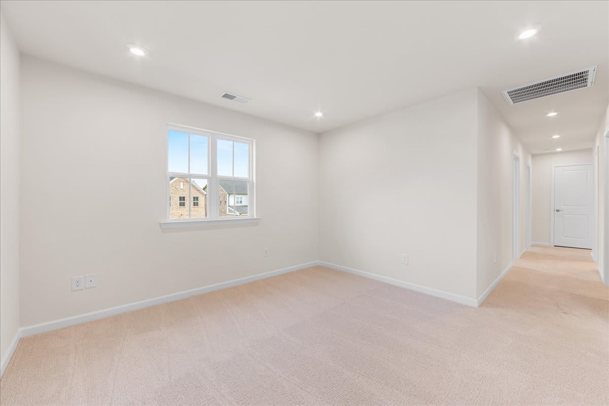 A bright, minimalist room with white walls, hardwood floors, and a window overlooking a residential neighborhood.