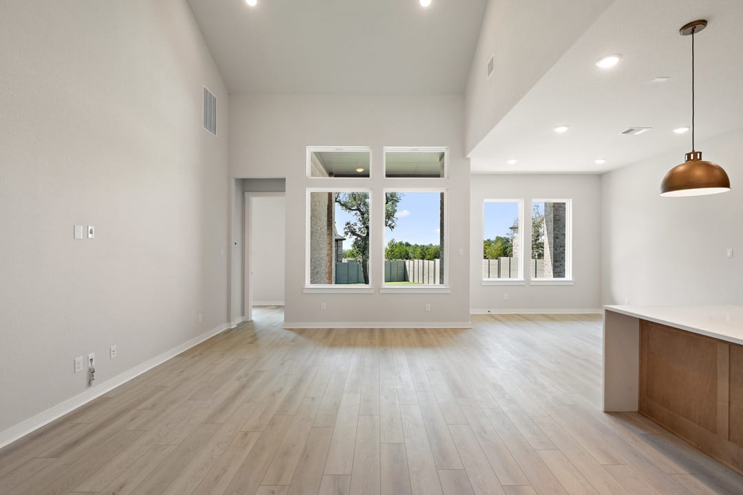 A bright and spacious room with large windows, hardwood floors, and a minimalist design aesthetic.