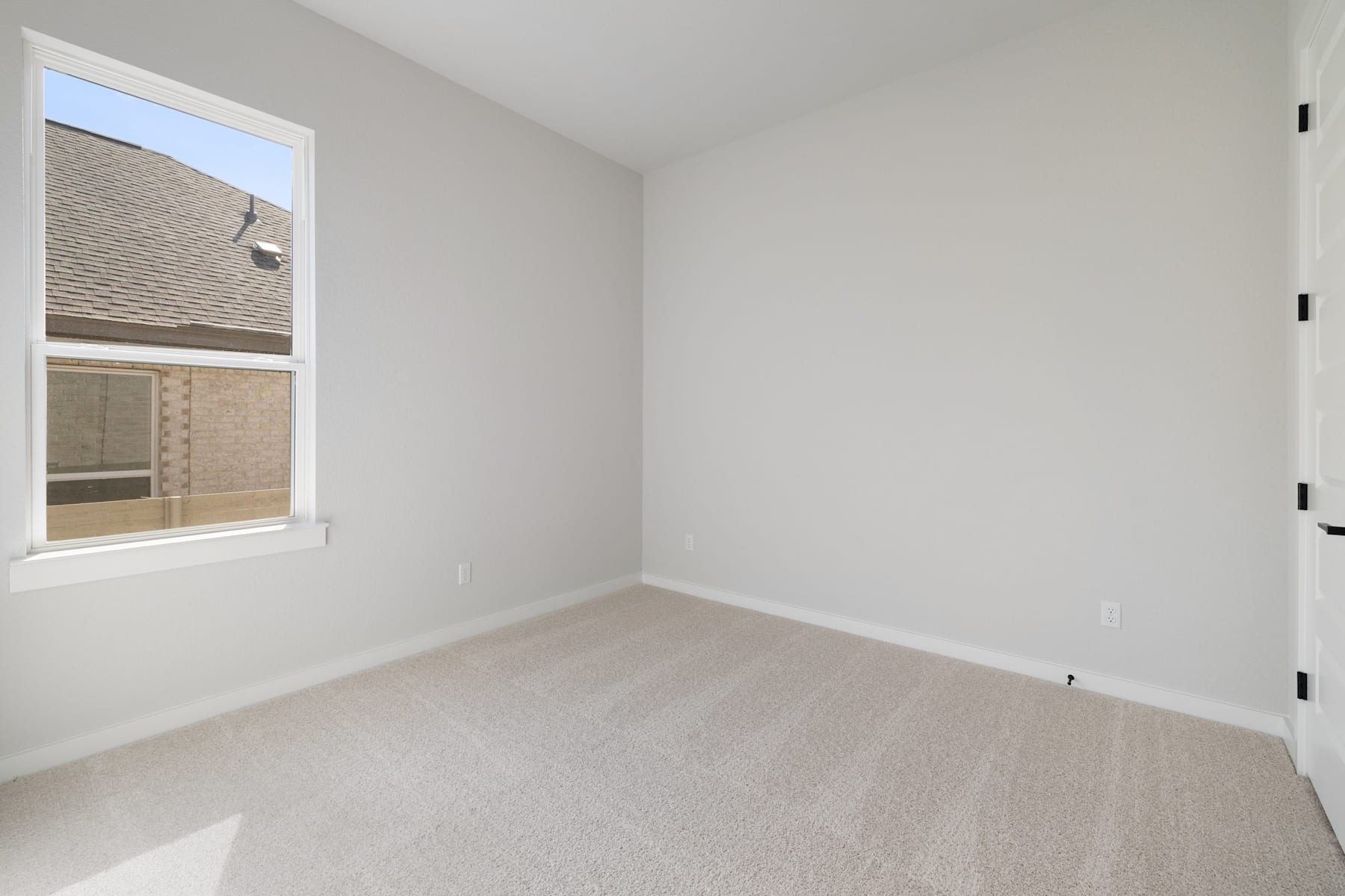 A sparsely furnished room with a window, white walls, and a light-colored floor.