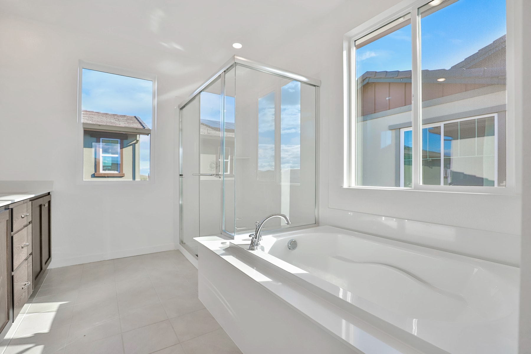 A modern, bright bathroom with a large bathtub, glass shower enclosure, and ample natural light from the windows.