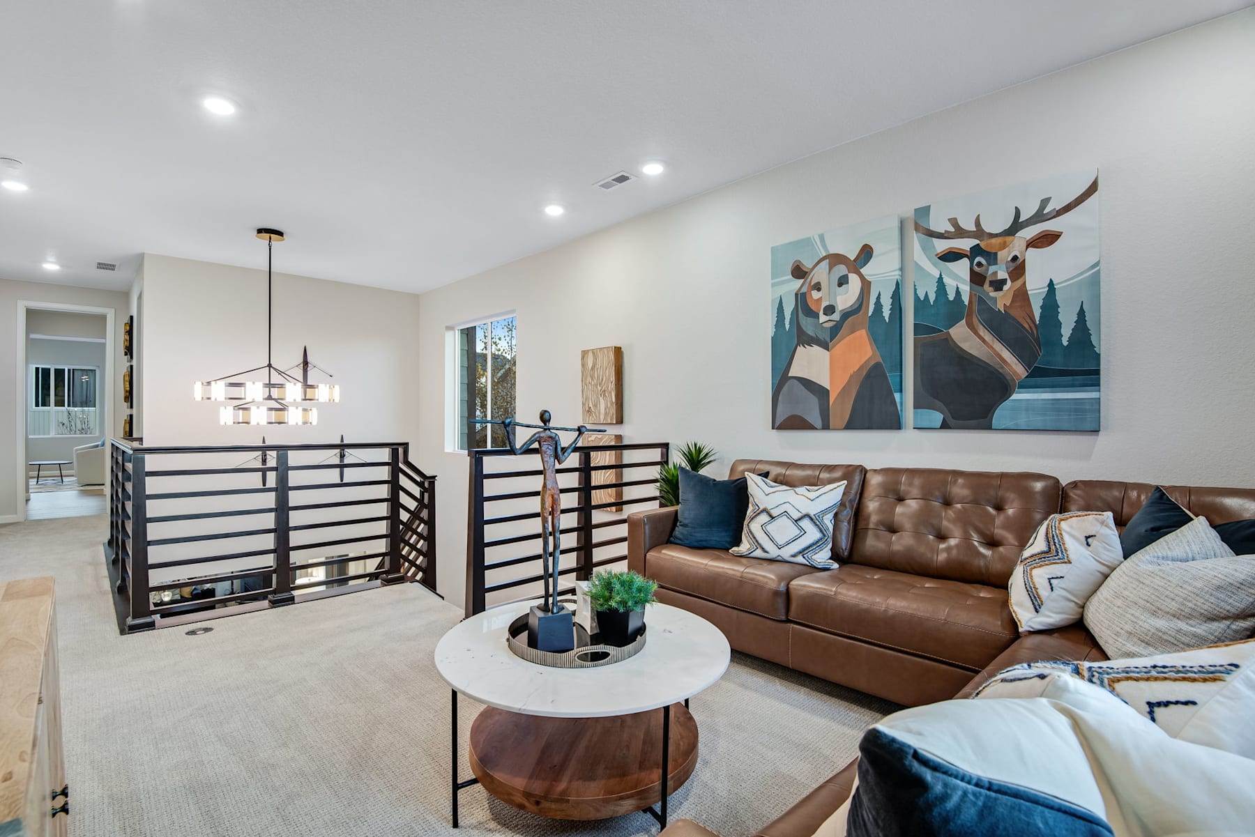 A cozy and modern living room with a leather sofa, a large painting of deer, and various decorative elements creating a warm and inviting atmosphere.