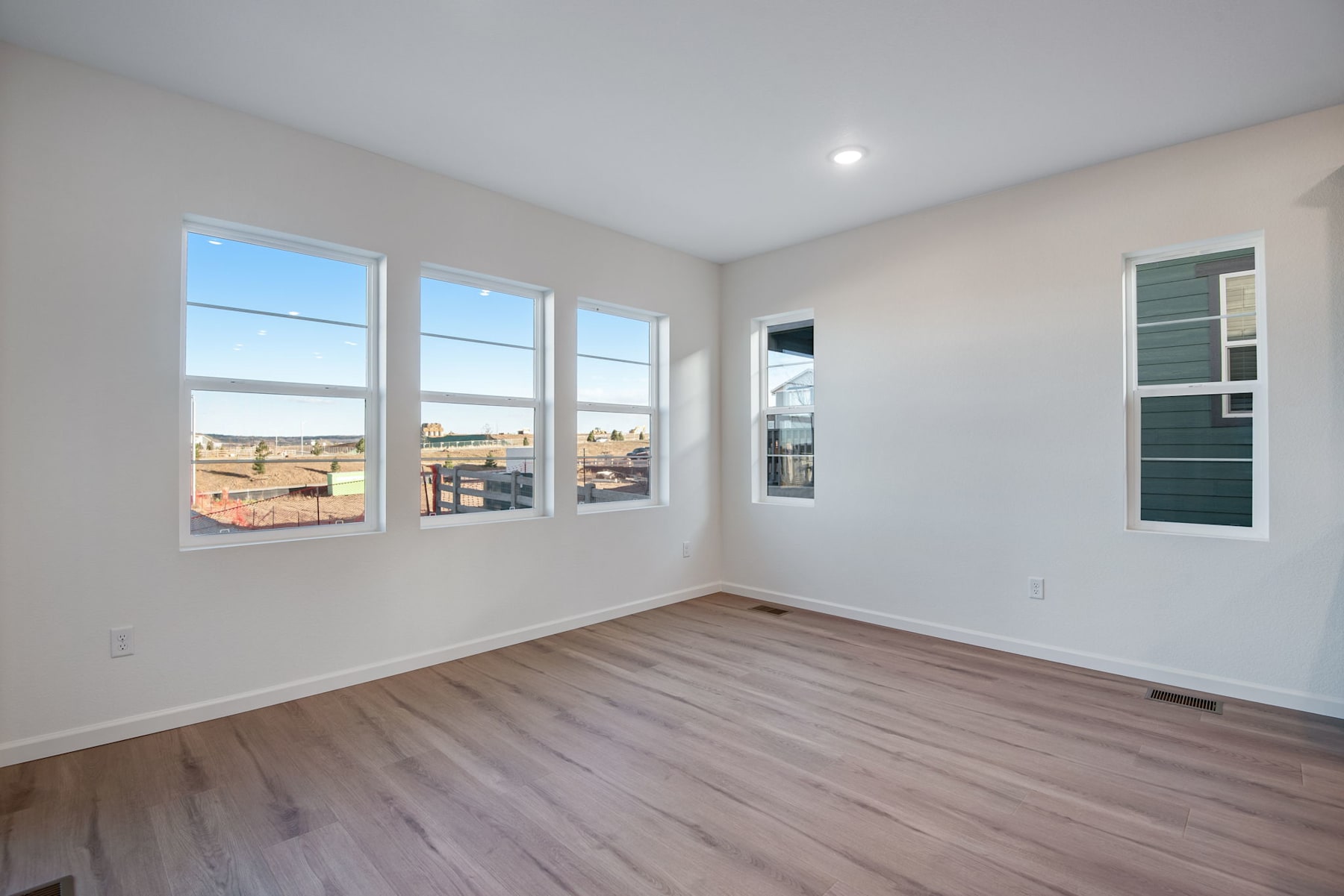 A bright and spacious room with large windows, hardwood floors, and a minimalist design.