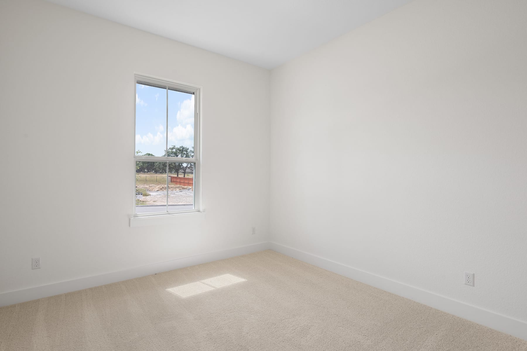 A bright, empty room with a window overlooking an outdoor area.
