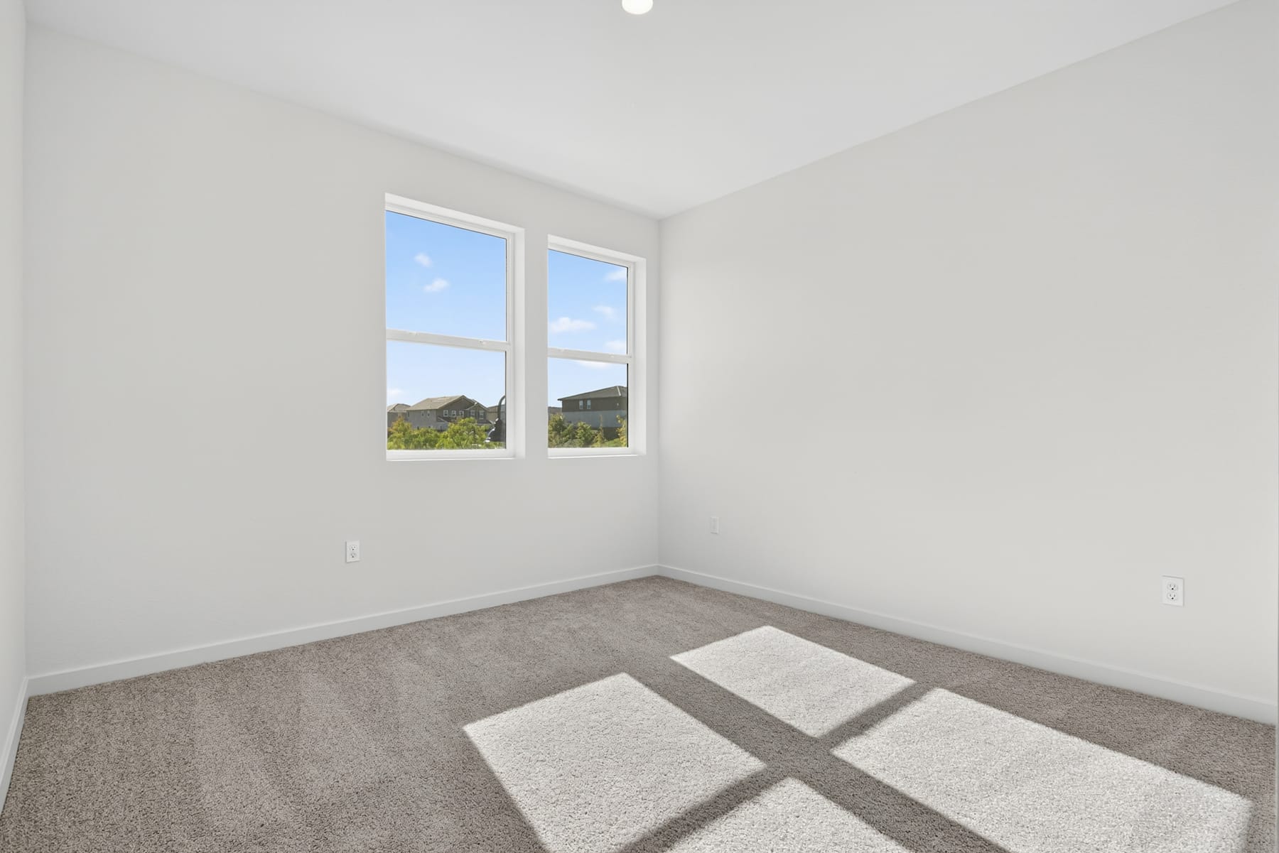 A bright, empty room with large windows overlooking a scenic outdoor landscape.