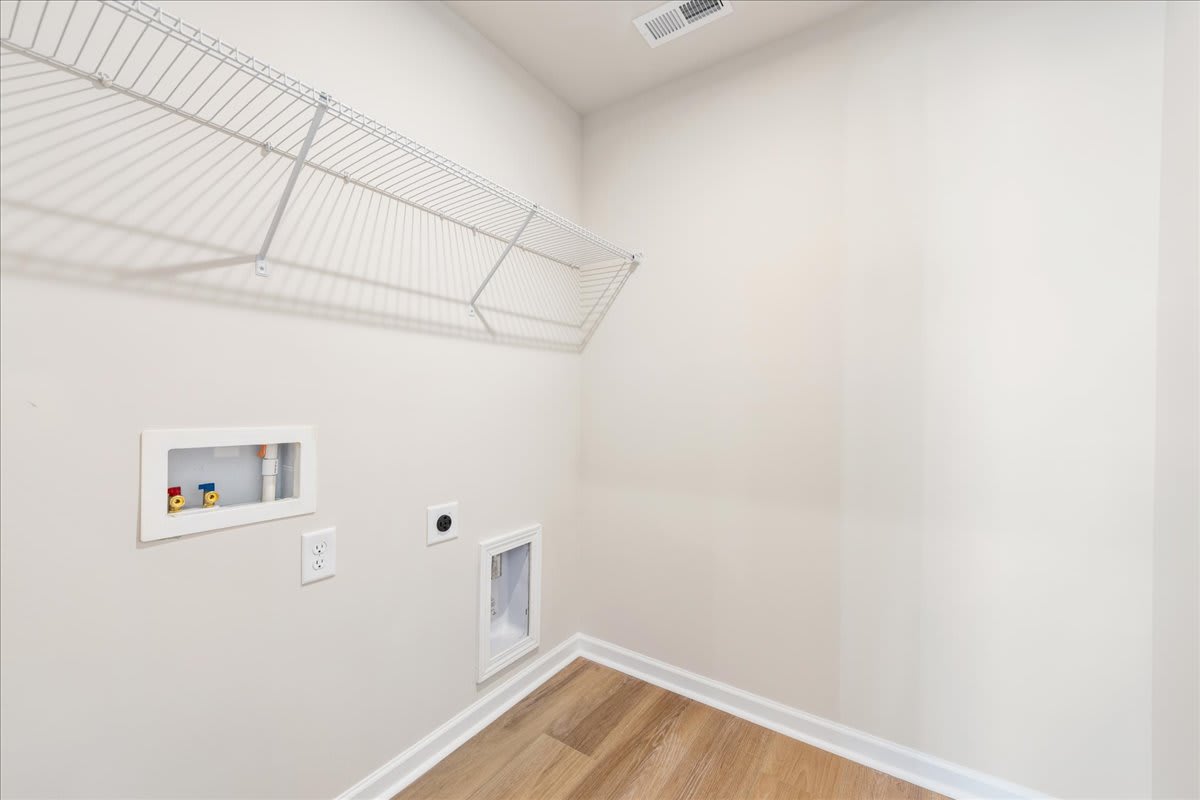 A small, bright room with a wire shelving unit and a light switch on the wall.