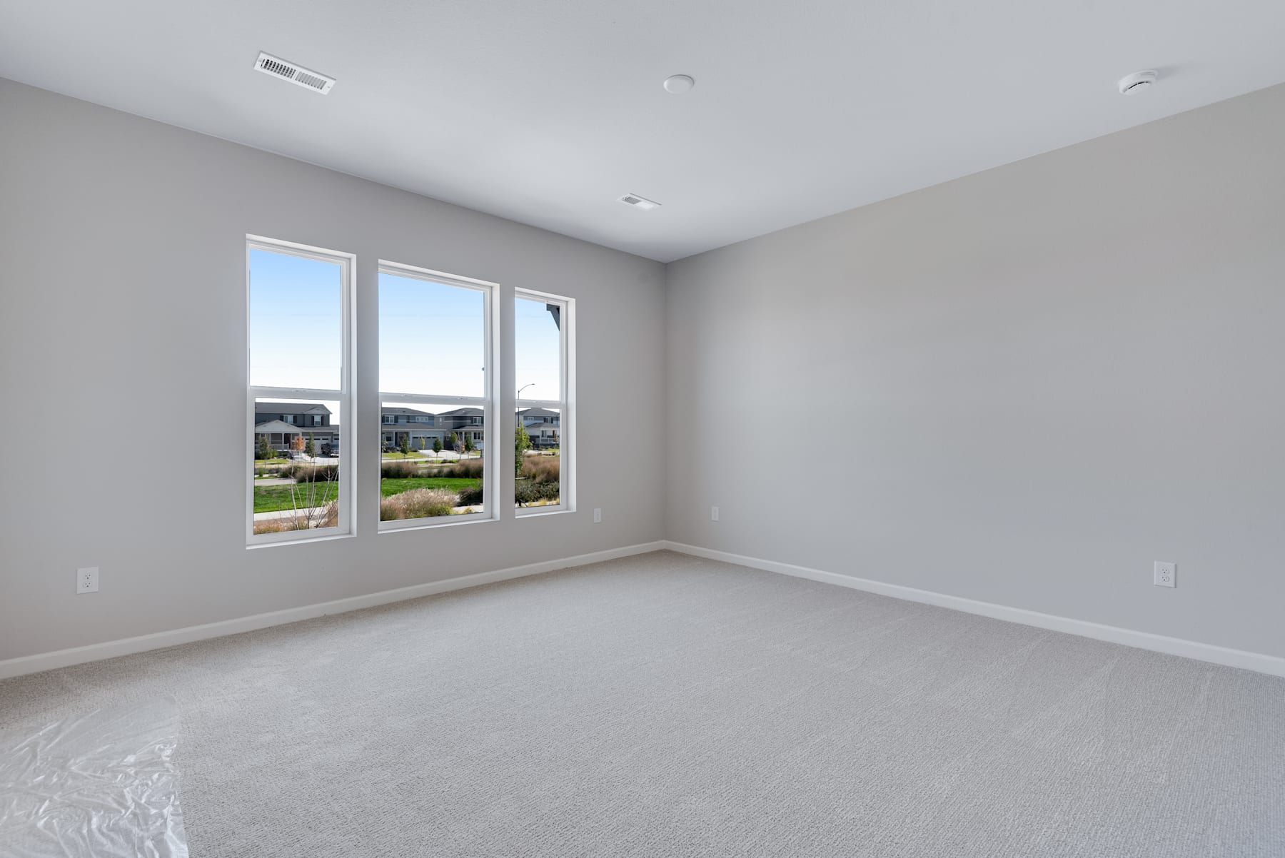 A spacious, well-lit room with large windows overlooking a grassy outdoor area, featuring a clean and minimalist interior design.
