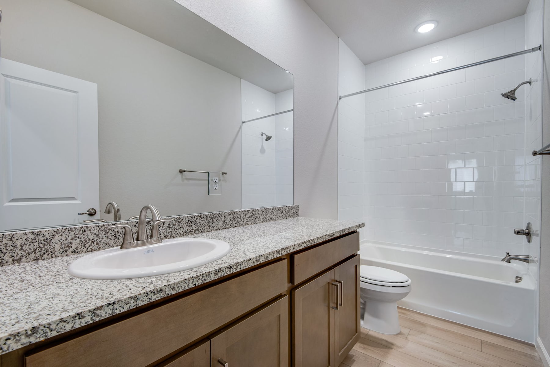 A modern bathroom with a vanity, sink, and toilet, featuring a granite countertop and tiled walls.