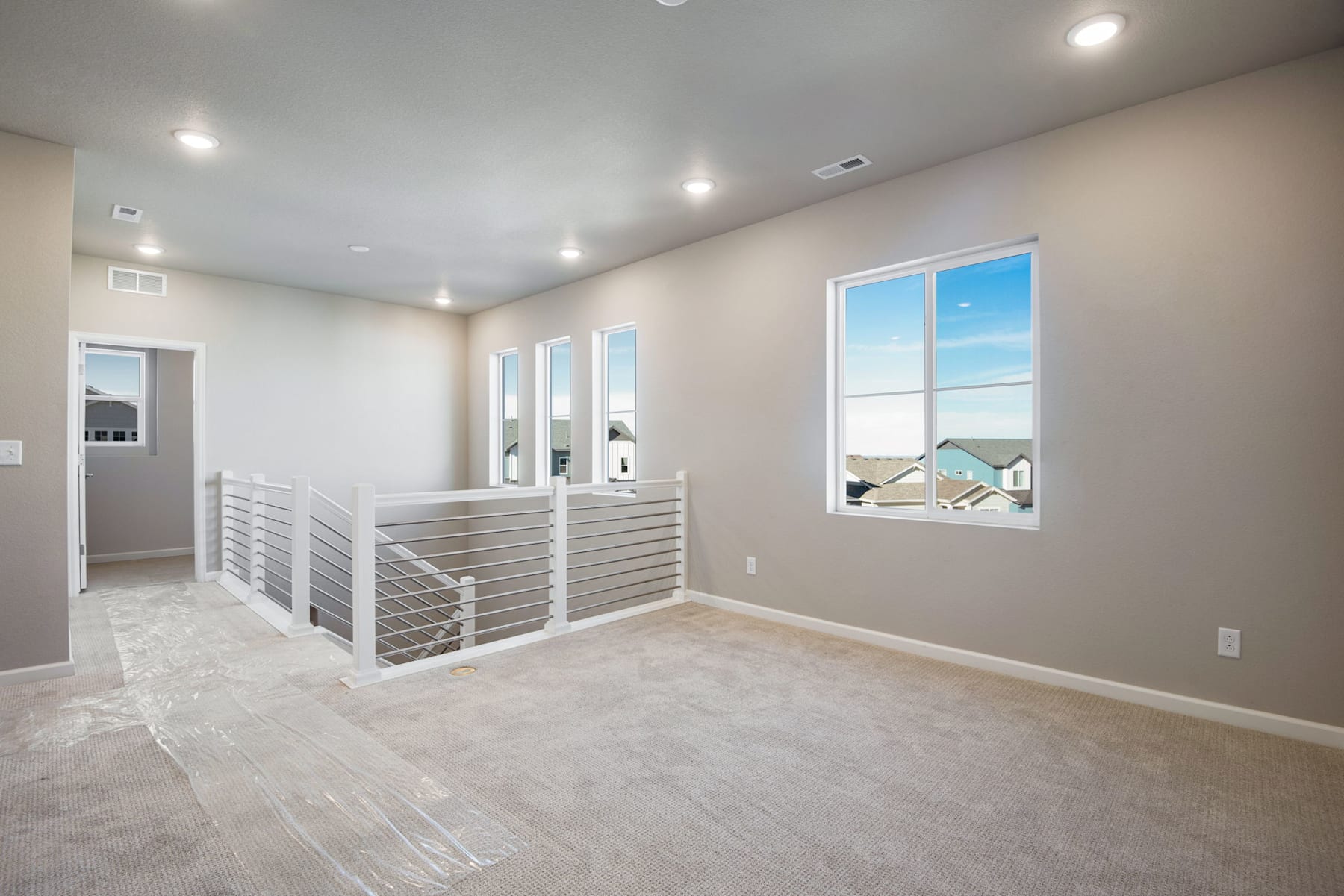 A spacious, well-lit room with a modern railing system and large windows overlooking a scenic outdoor landscape.