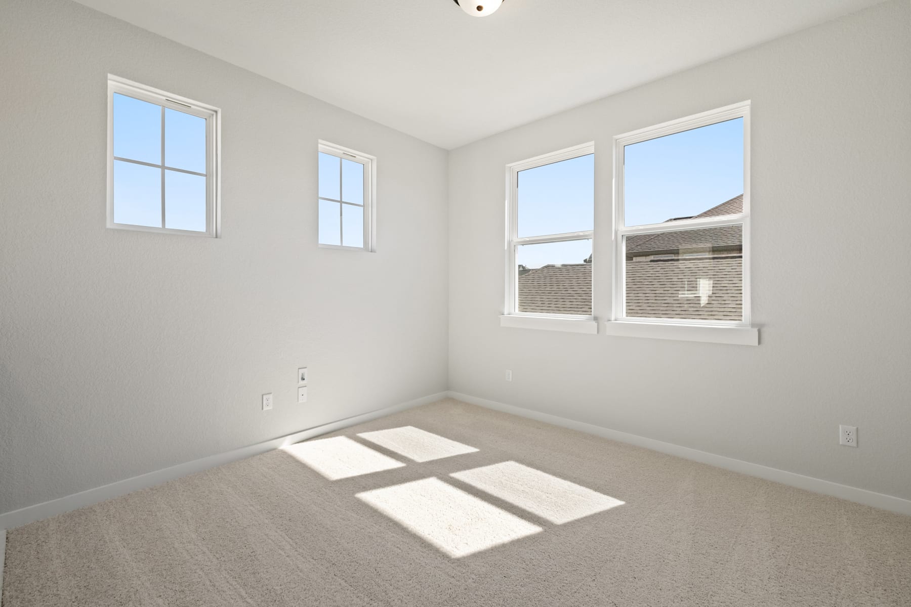 A bright, empty room with white walls, windows, and a hardwood floor, creating a clean and minimalist atmosphere.