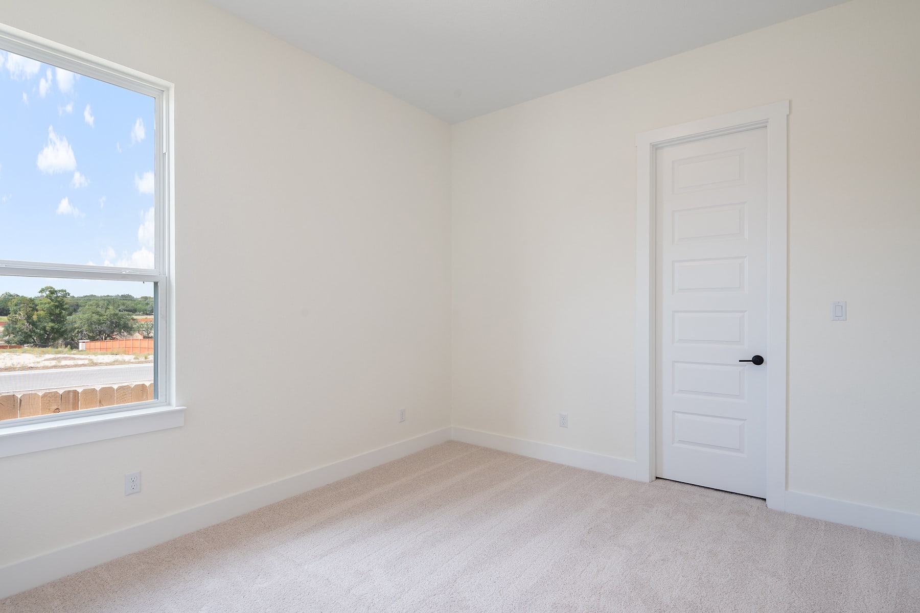 A bright, empty room with a large window overlooking a scenic outdoor landscape.