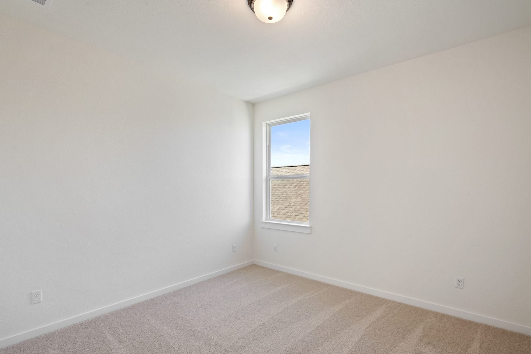 A simple, minimalist room with a single window, a light fixture, and a hardwood floor.