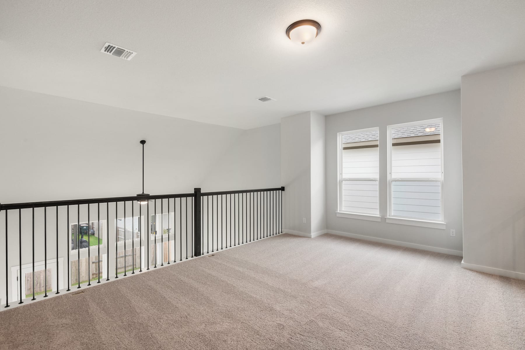 A spacious, well-lit room with a balcony railing and a ceiling light fixture, featuring a clean and minimalist design.