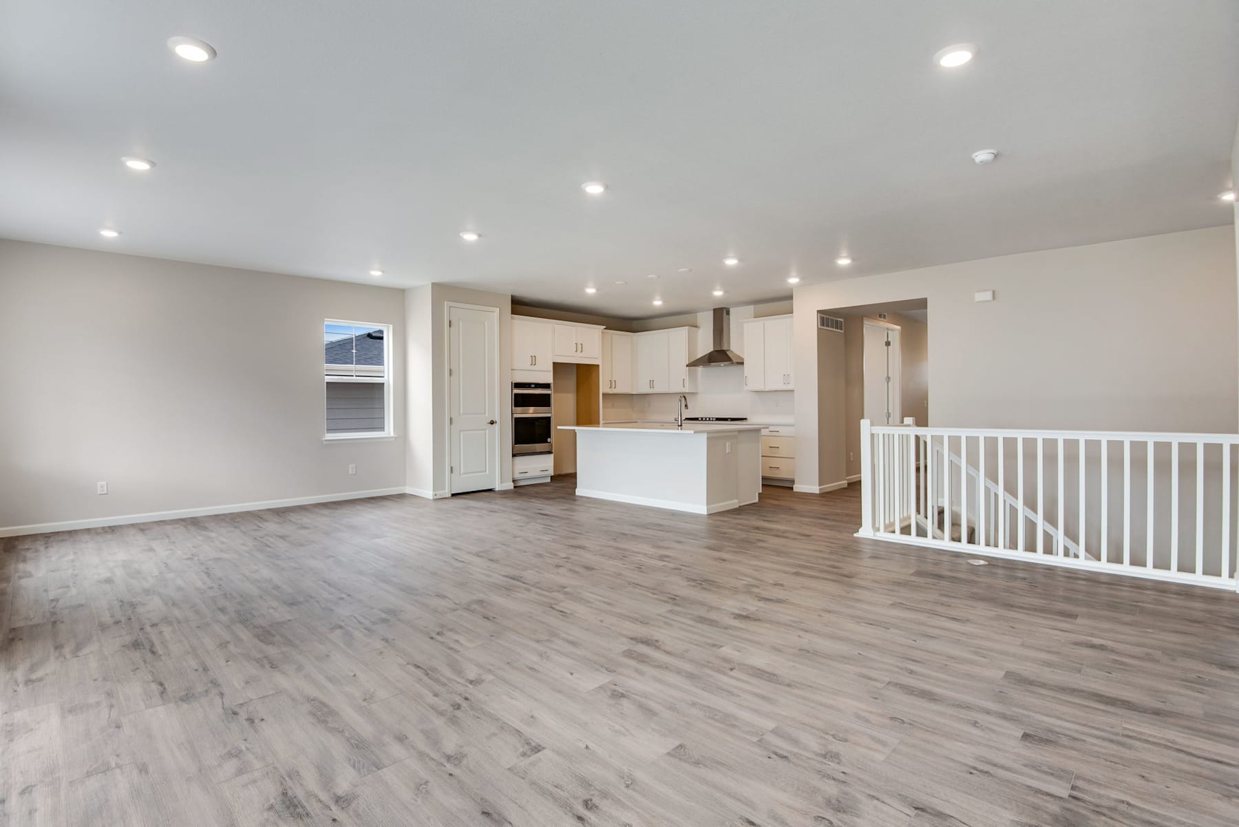 A spacious, open-concept living area with a modern kitchen, hardwood-style flooring, and recessed lighting, creating a bright and airy atmosphere.
