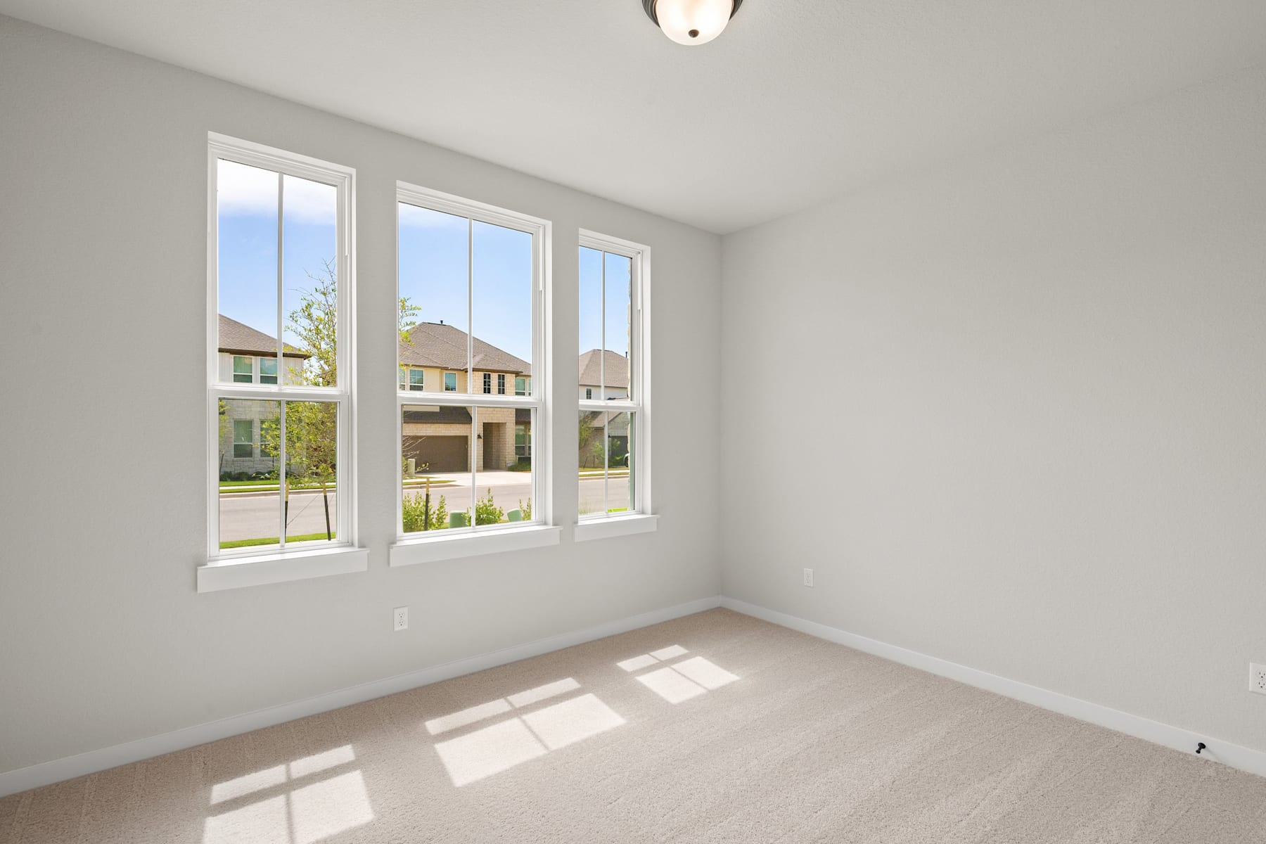 A bright and airy room with large windows overlooking a residential neighborhood, featuring a clean and minimalist interior design.