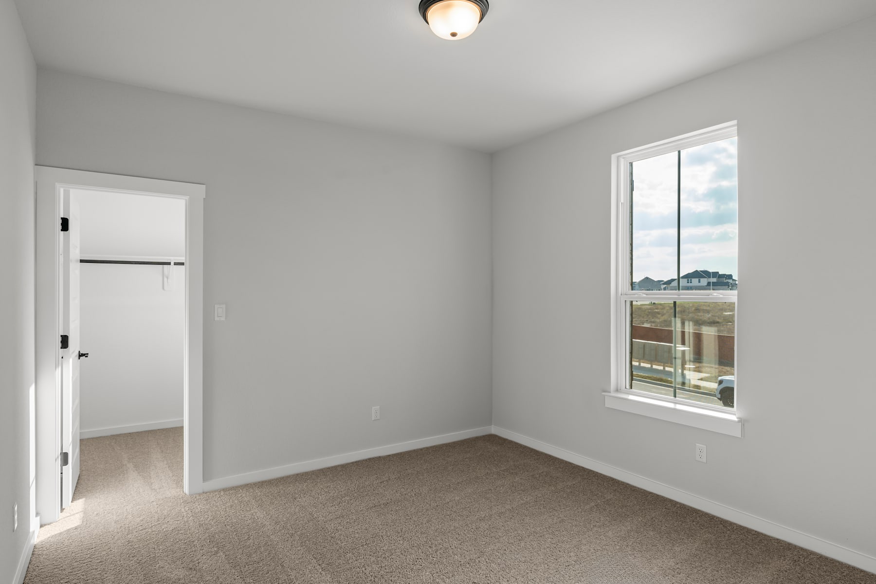 A simple, minimalist bedroom with a window overlooking a scenic outdoor landscape.
