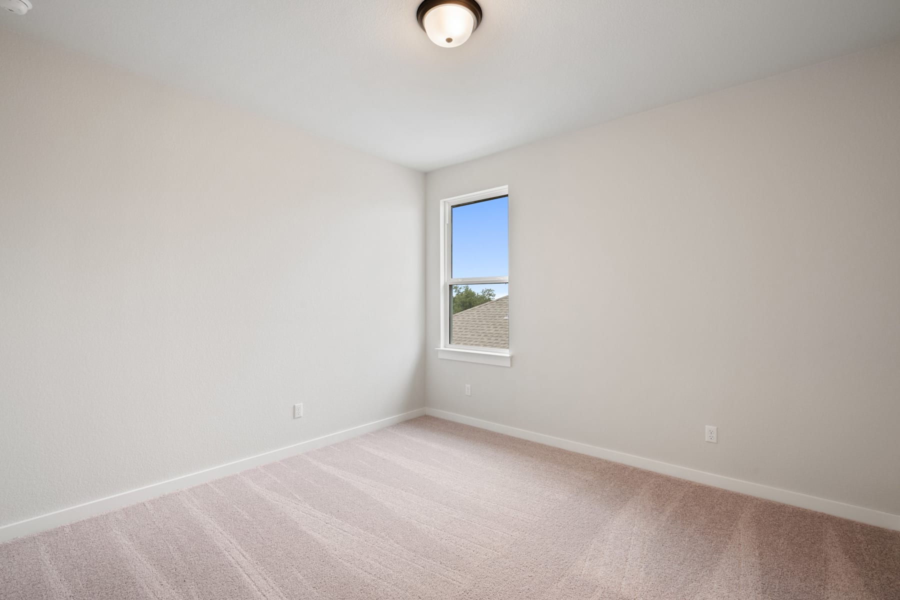 A simple, minimalist room with a single window overlooking an outdoor landscape, featuring a plain white wall and a hardwood floor.