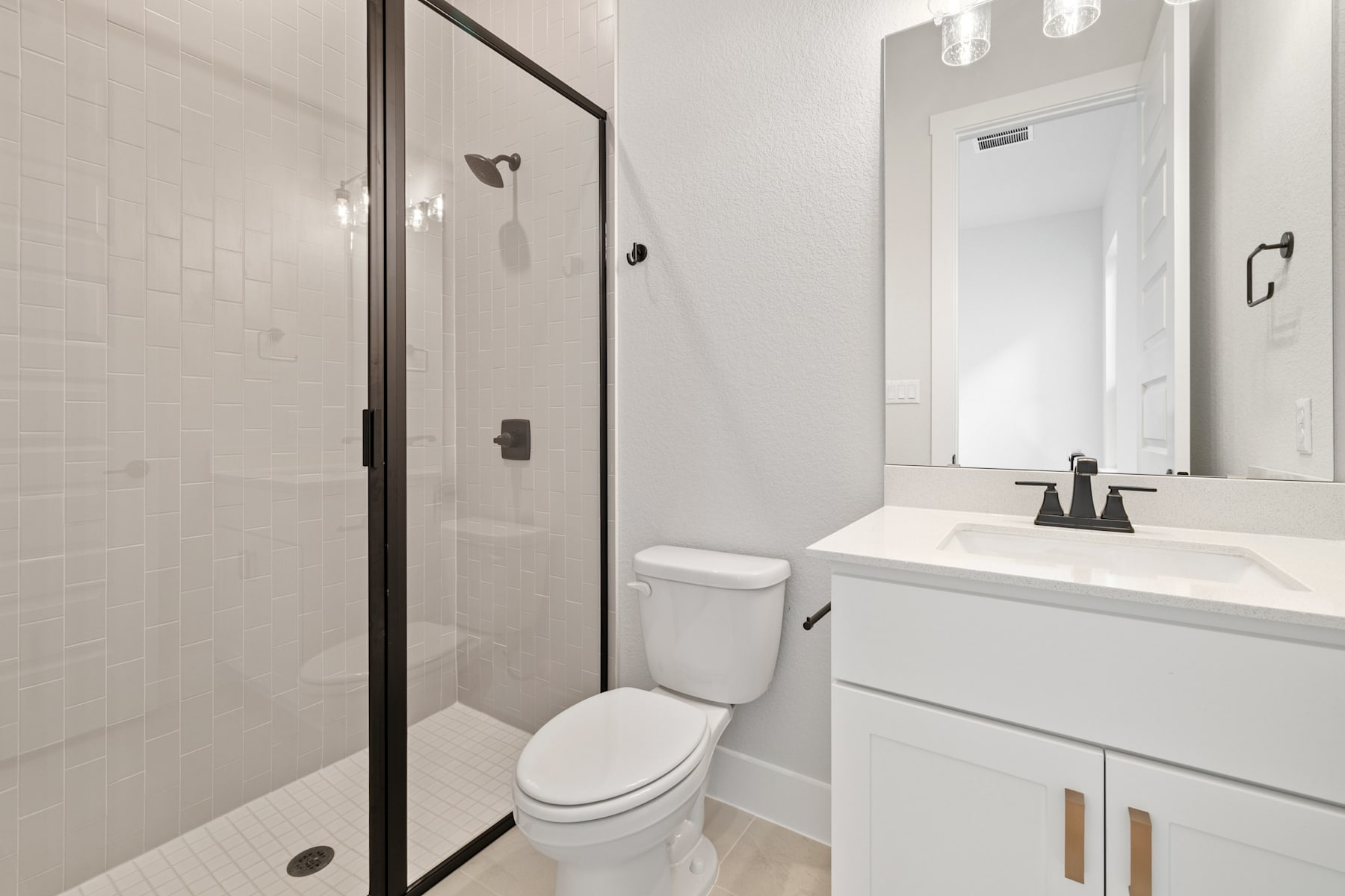 A modern, minimalist bathroom with a white vanity, a toilet, and a glass-enclosed shower stall.
