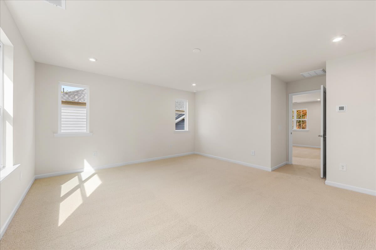 A bright and spacious room with white walls, a large window, and a hardwood floor. The room appears to be empty, with no furniture or decor visible.