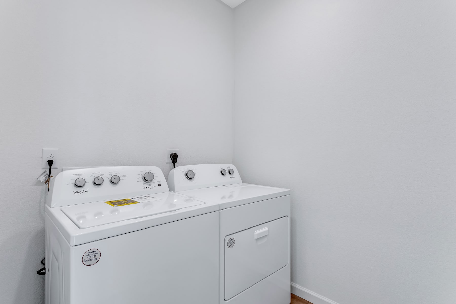A small, white laundry room with a washer and dryer set against the wall.