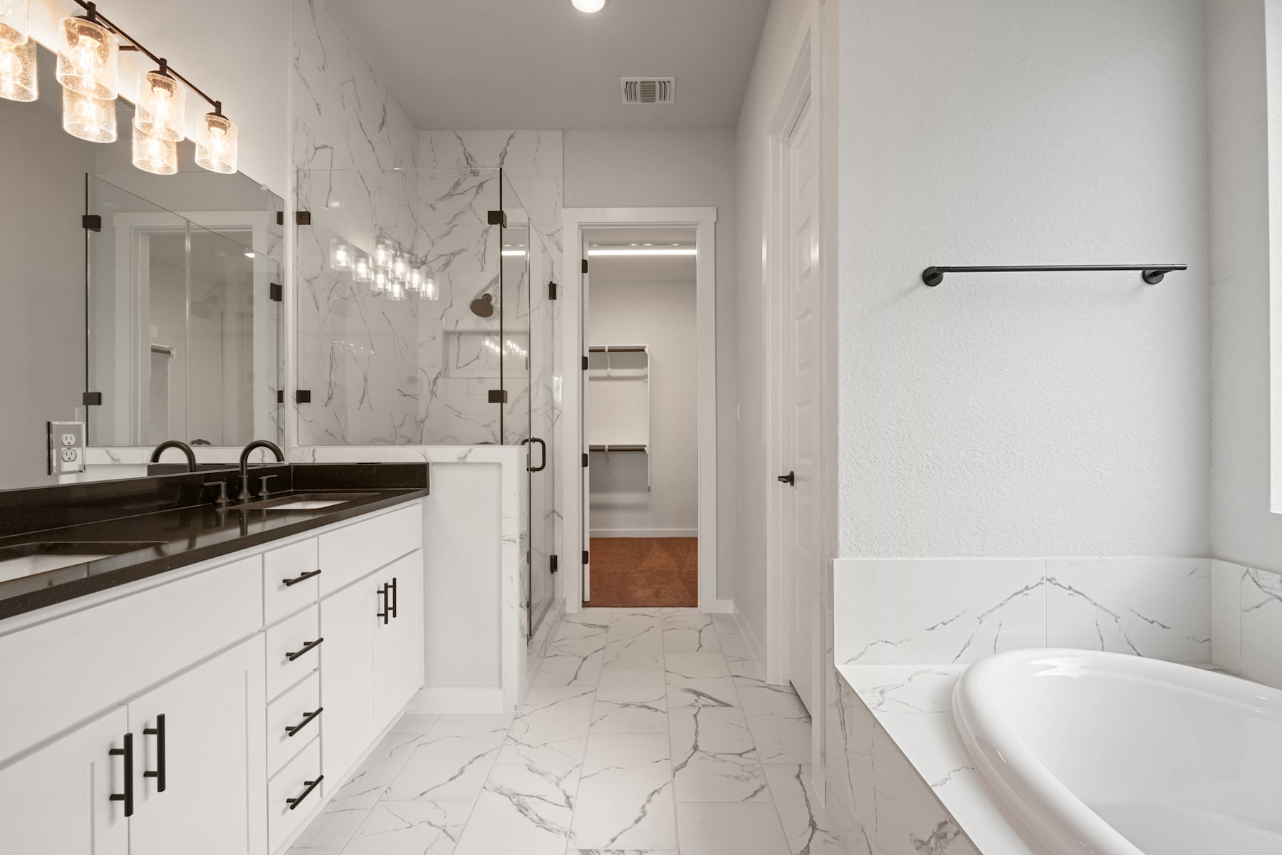 A modern, minimalist bathroom with white cabinets, a marble-patterned countertop, and a freestanding bathtub in the background.