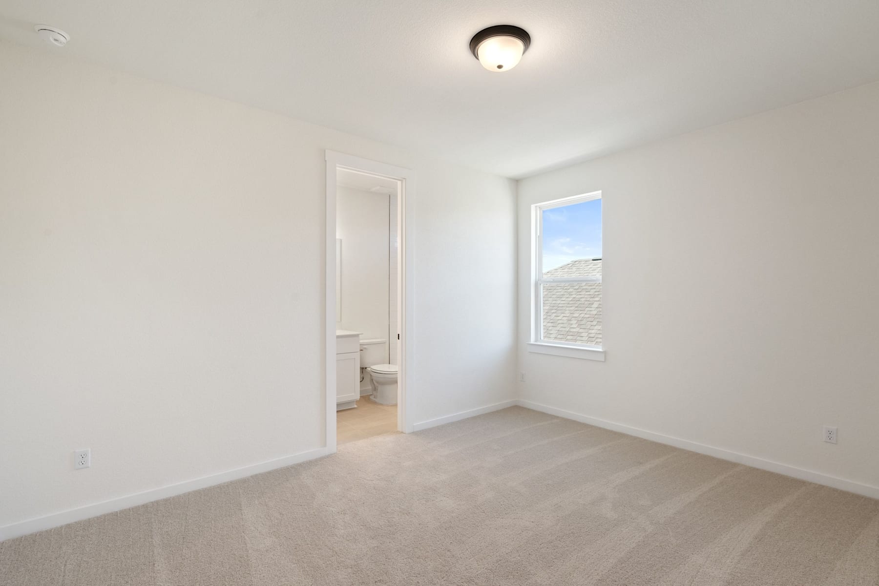 A bright, minimalist bedroom with a window, a ceiling light, and a doorway leading to another room.