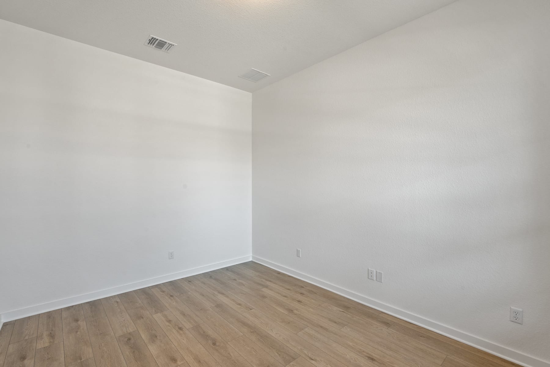 An empty room with white walls and a wooden floor, providing a clean and minimalist space.
