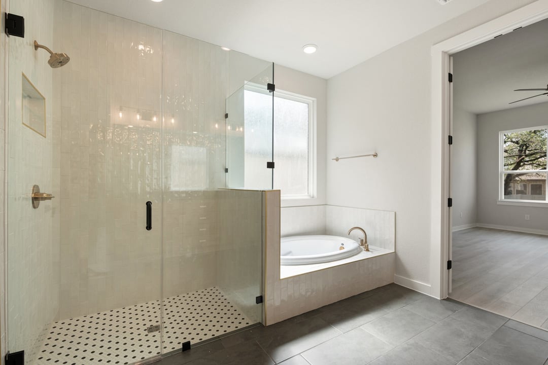 A modern, minimalist bathroom with a glass-enclosed shower, a freestanding bathtub, and a neutral color scheme.