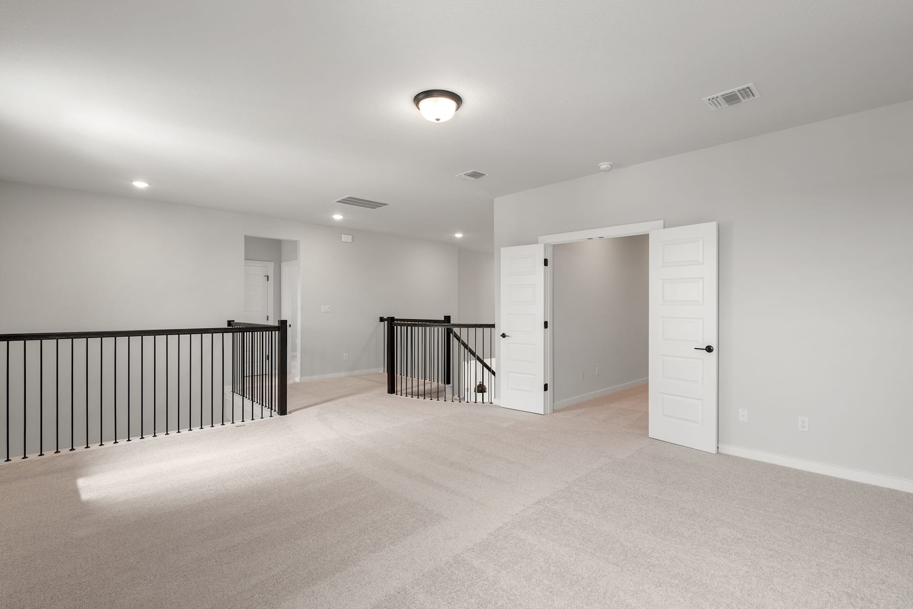 A spacious, well-lit hallway with a railing and white doors leading to various rooms, showcasing a minimalist and modern interior design.