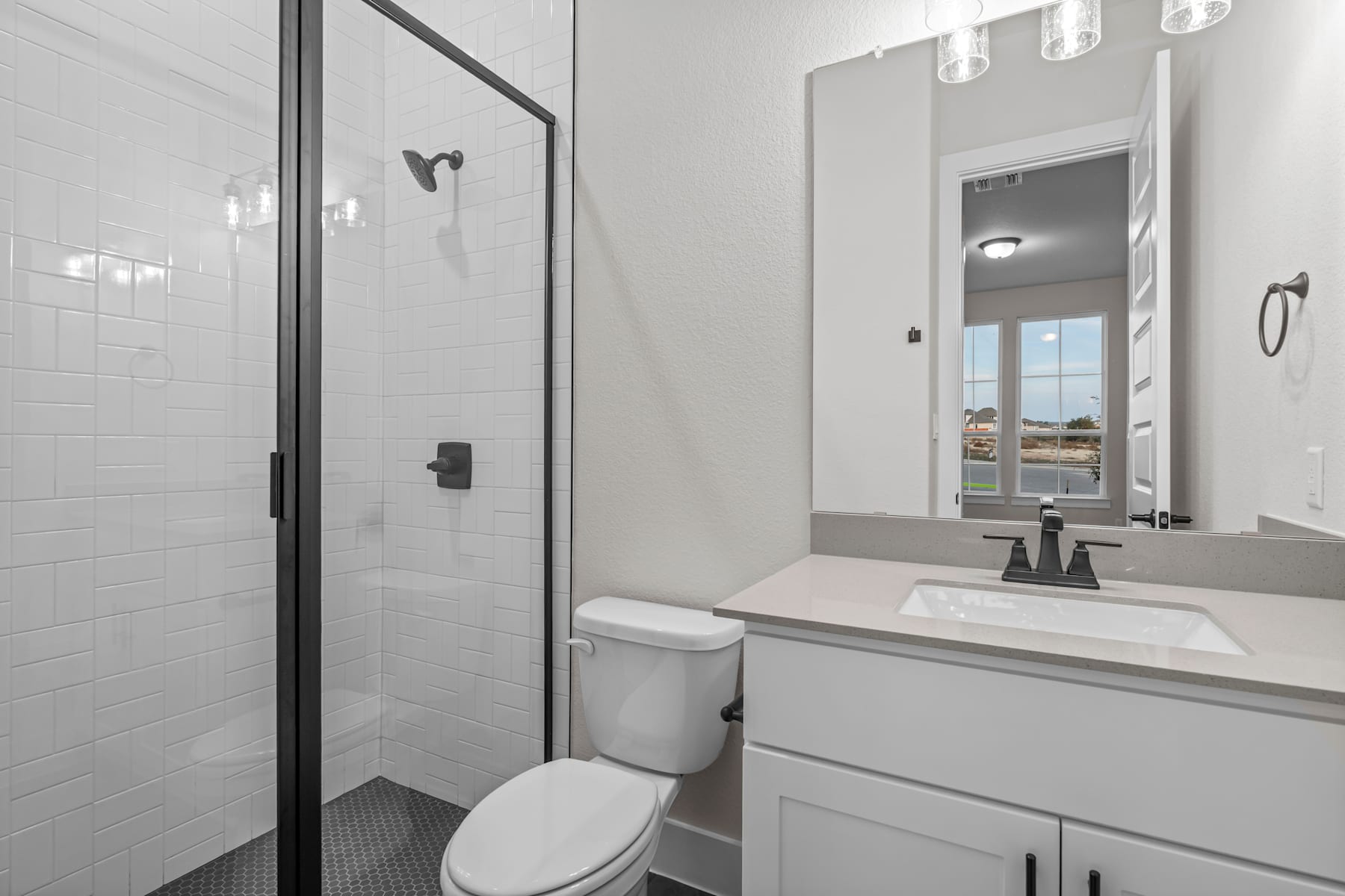 A modern, minimalist bathroom with a white vanity, a mirror, and a glass-enclosed shower area.