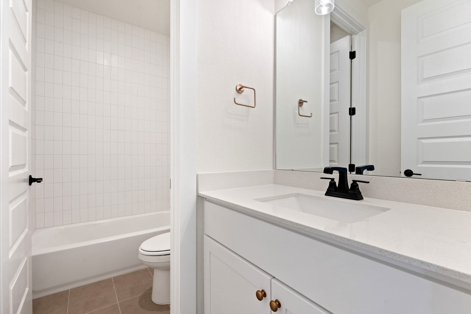 A modern, minimalist bathroom with a white vanity, black faucet, and a shower enclosure in the background.