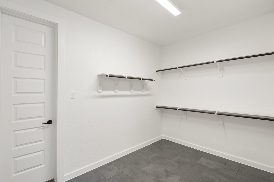 A white, minimalist closet with multiple shelves and hanging rods, providing ample storage space.