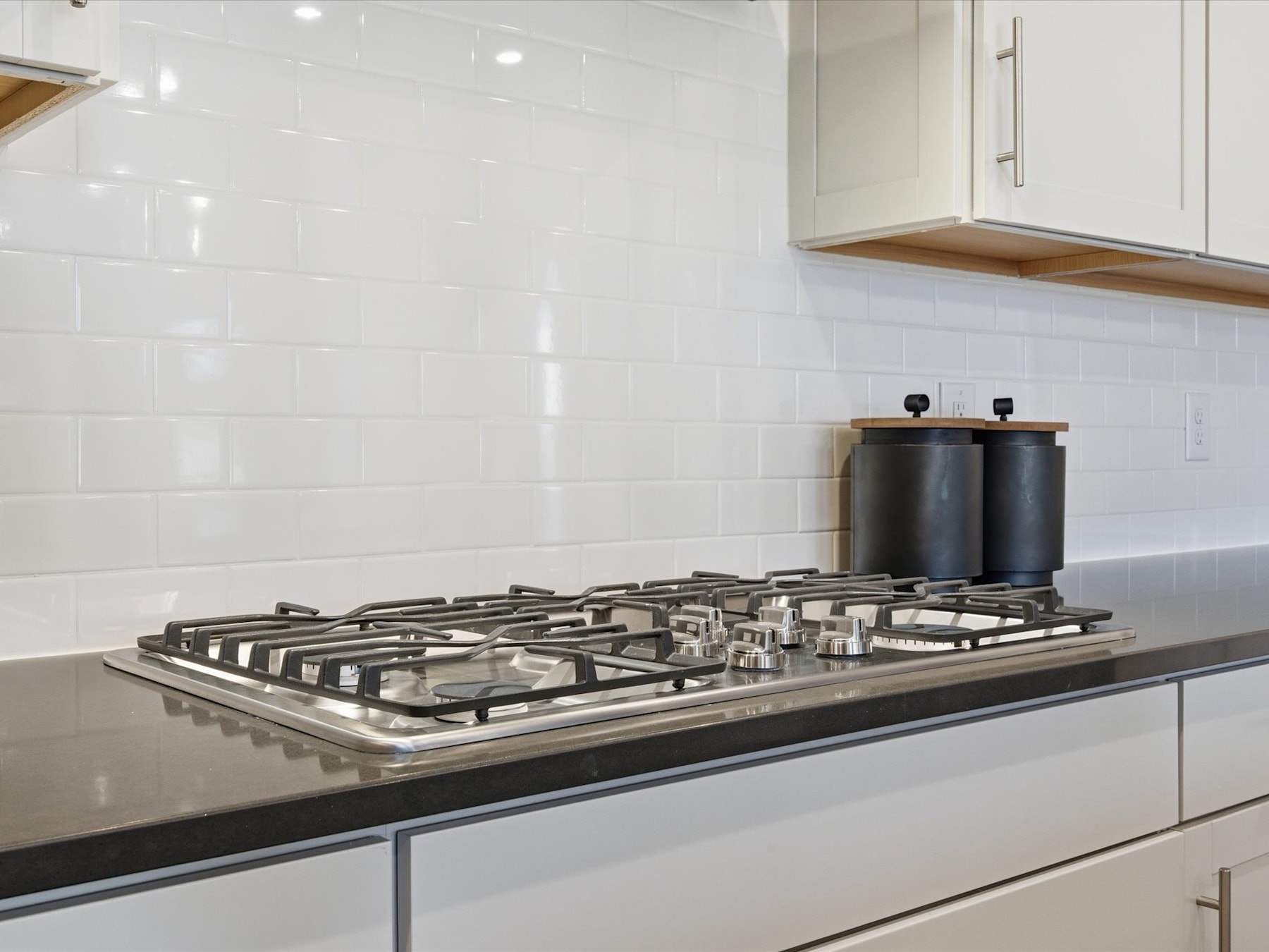 A modern kitchen with a sleek gas stove top and white cabinets in the background.