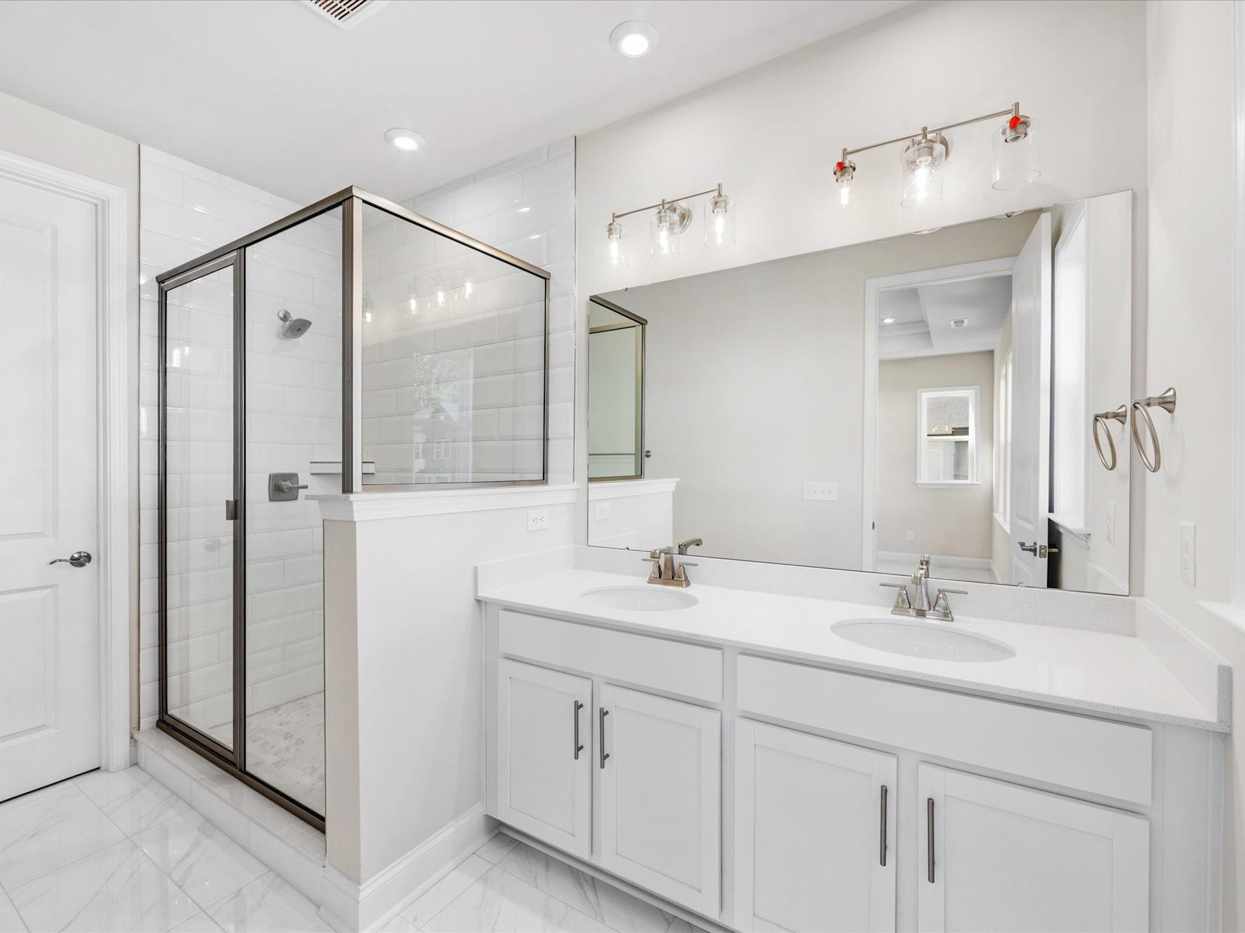 A modern, well-lit bathroom with a large vanity, a mirror, and a glass-enclosed shower.