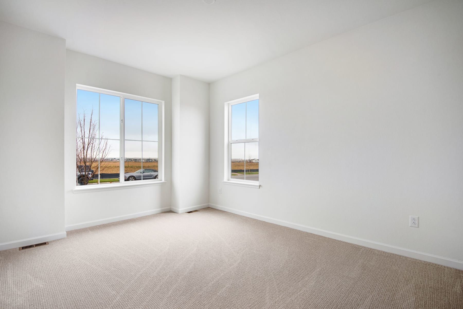 A bright, empty room with large windows overlooking a landscape in the background.